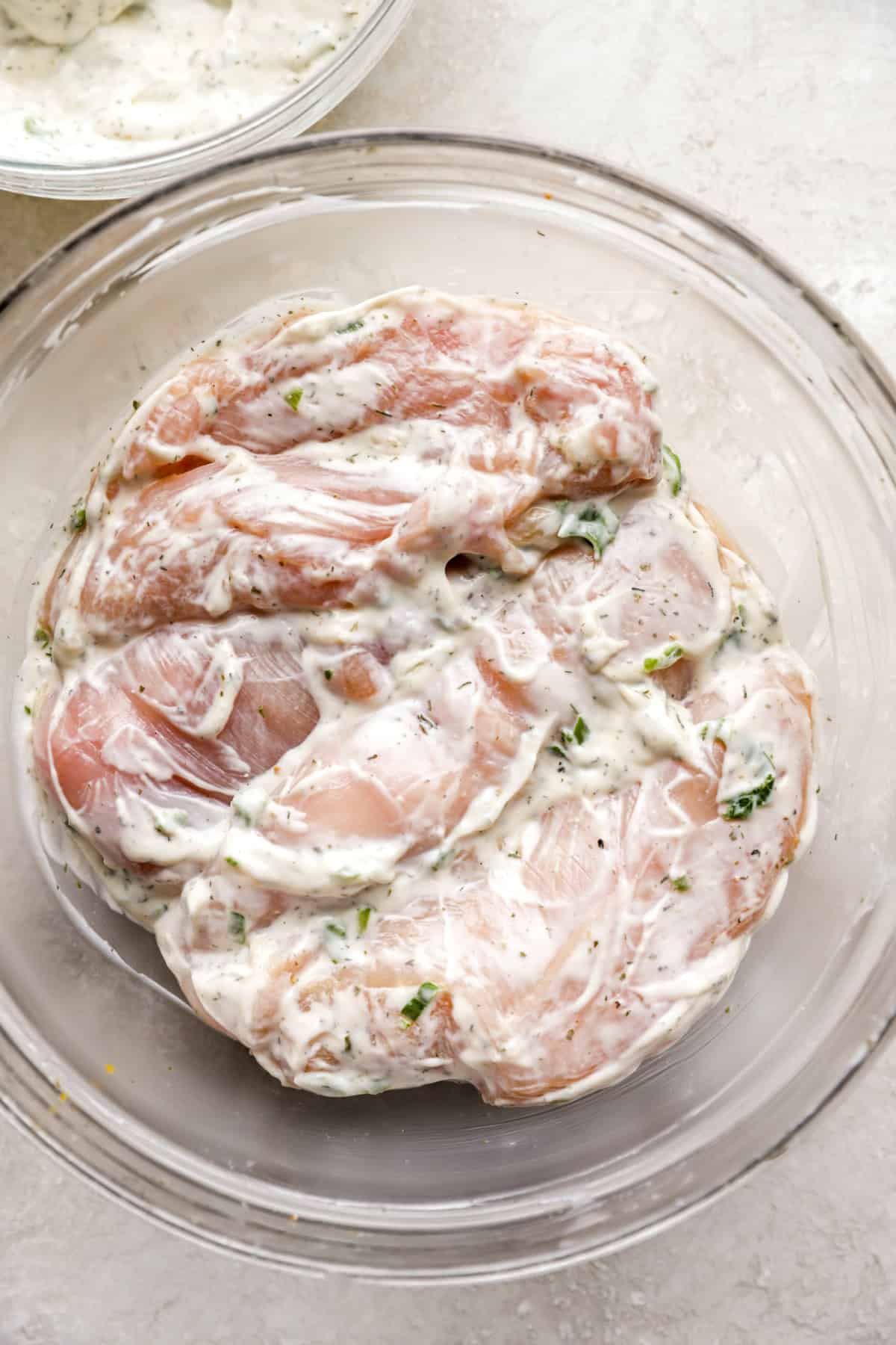 Raw chicken in a bowl of Ranch dressing. 