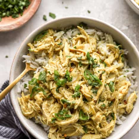 A bowl of crockpot chicken curry over white rice.