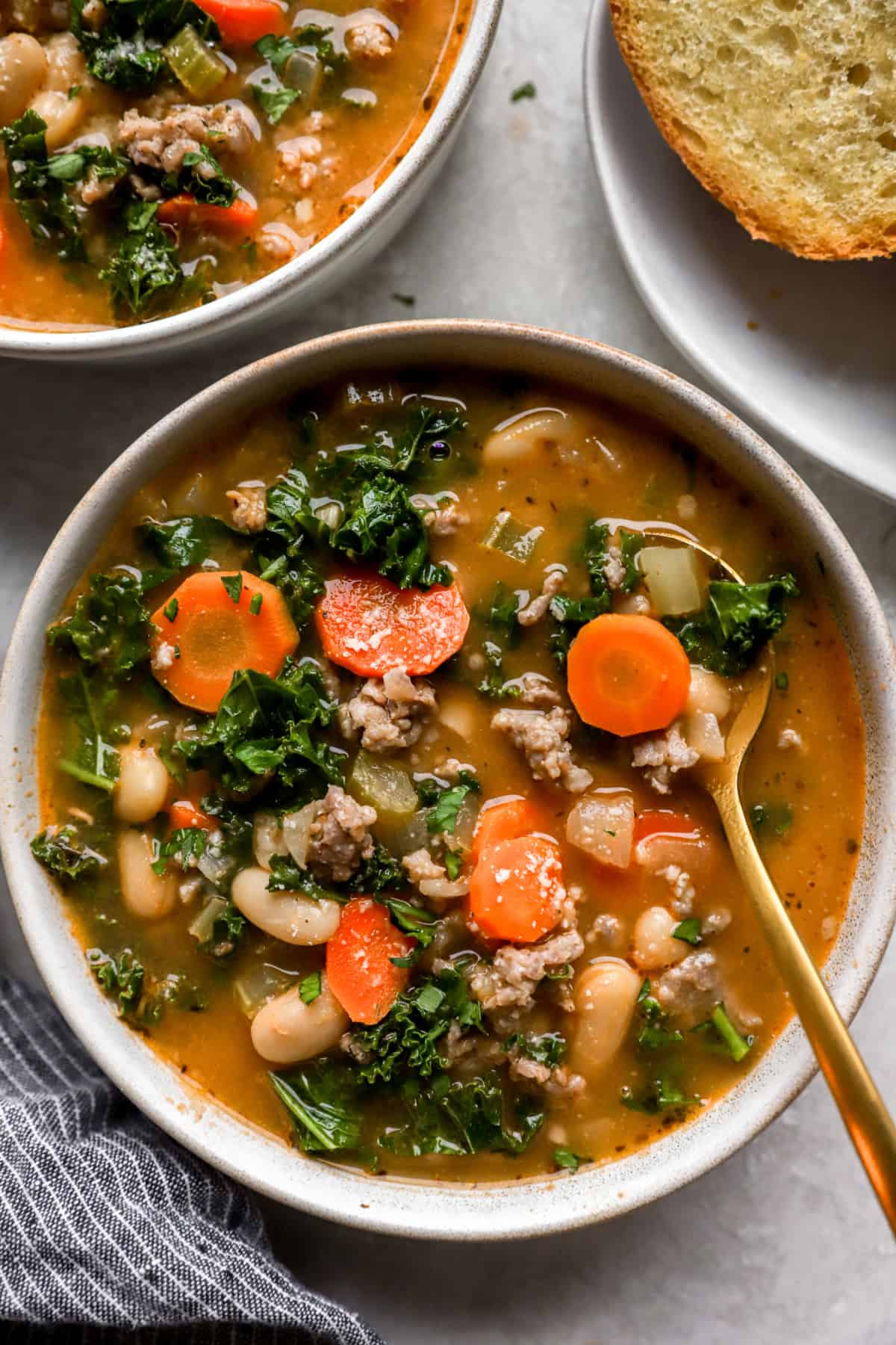 A bowl of Tuscan white bean soup with a spoon sticking out. 