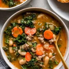 A bowl of Tuscan white bean soup with a spoon sticking out.