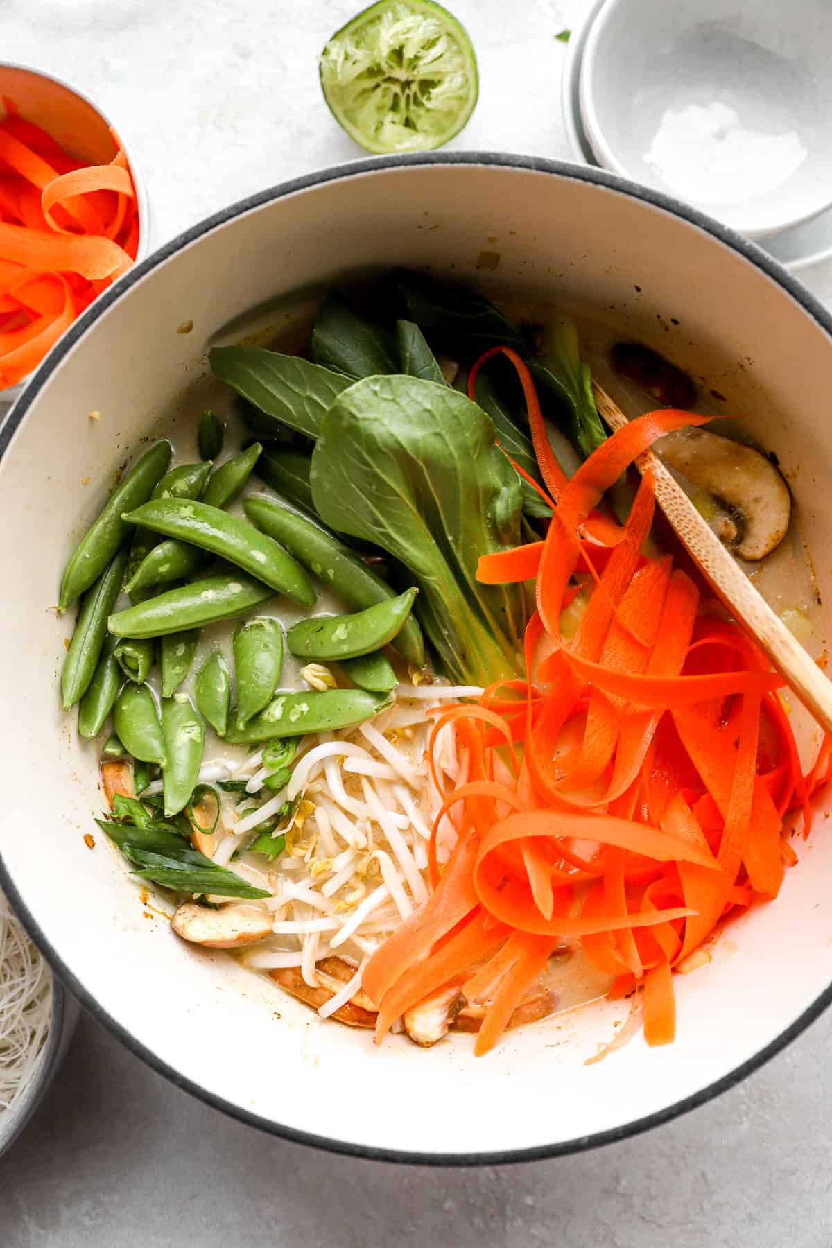 Veggies being stirred into a pot of coconut curry ramen. 