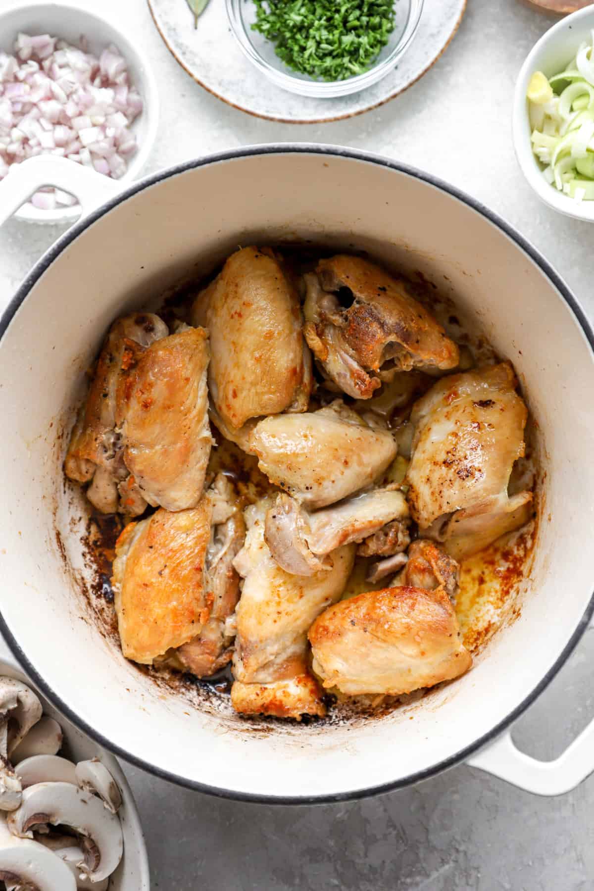 Chicken thighs browning in a Dutch oven.