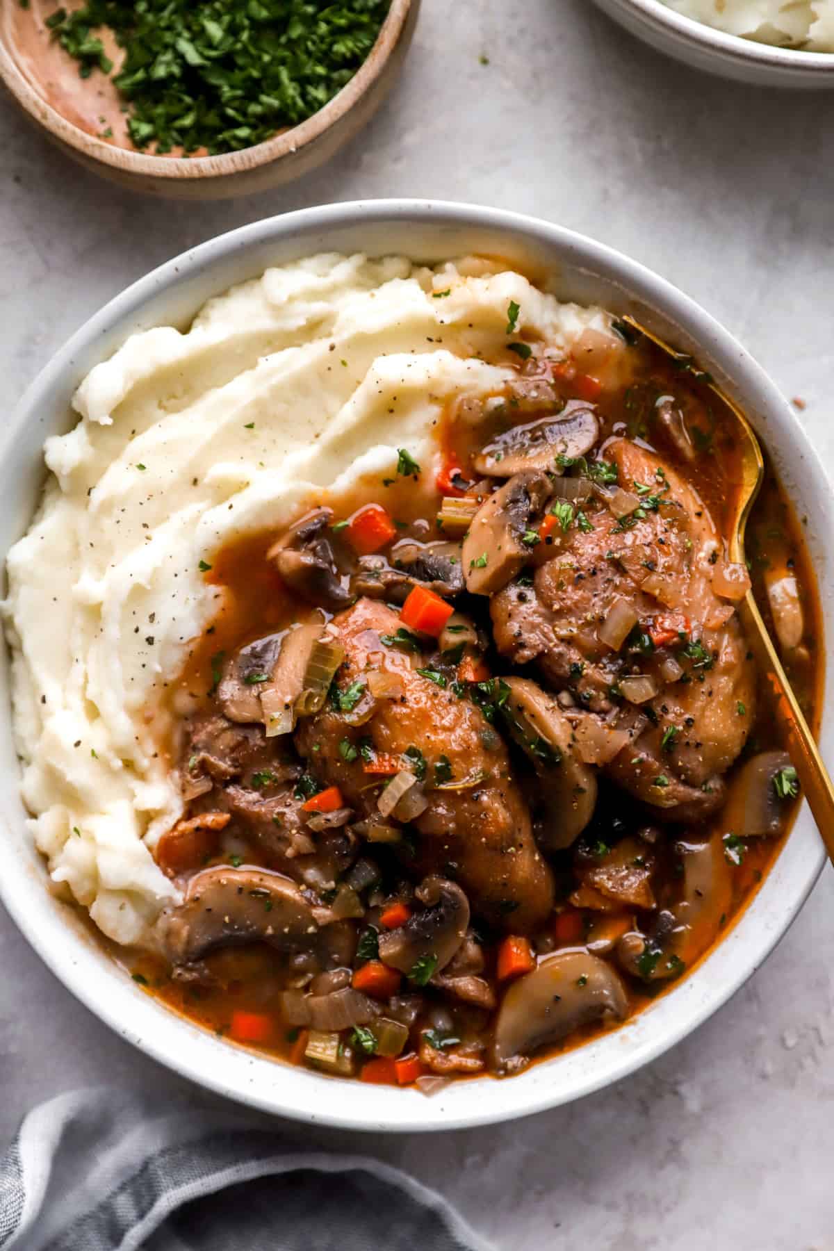 A bowl of chicken coq au vin over mashed potatoes.