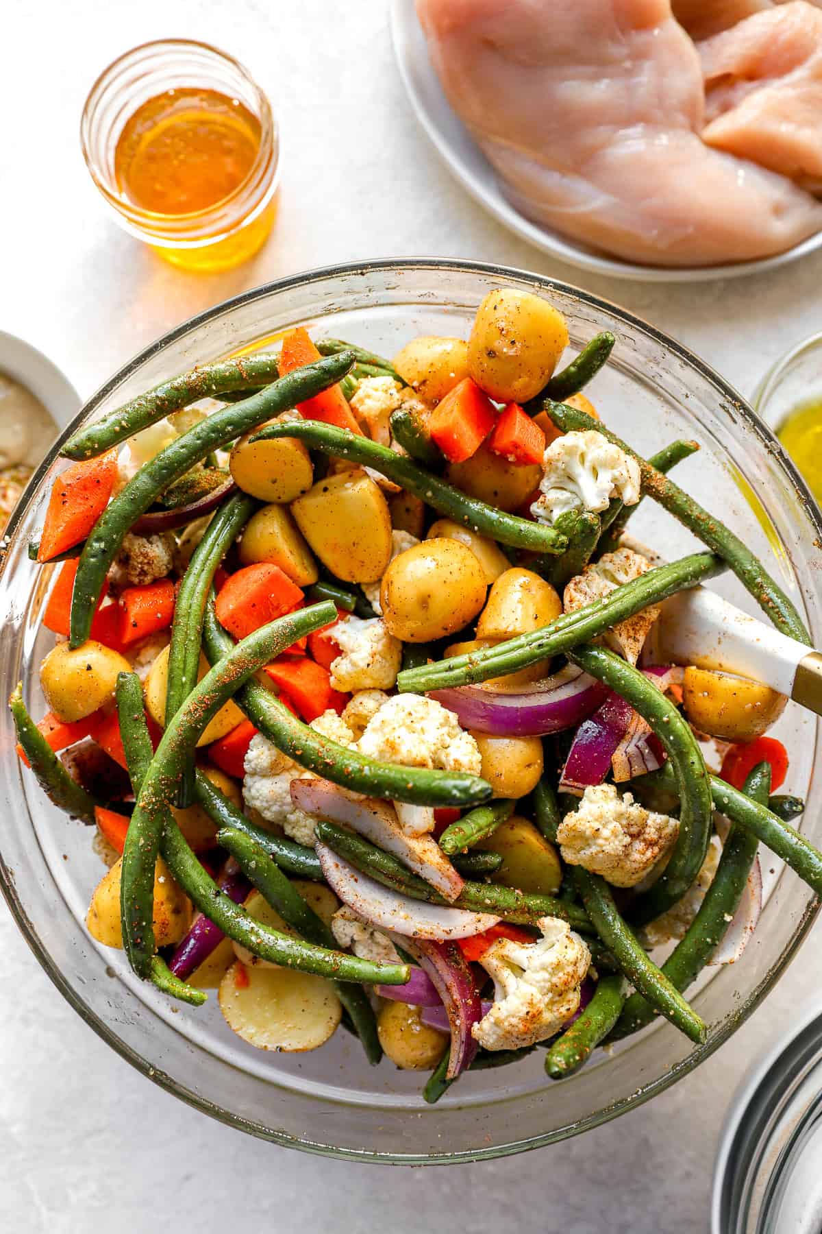 Vegetables in a bowl tossed with seasonings. 