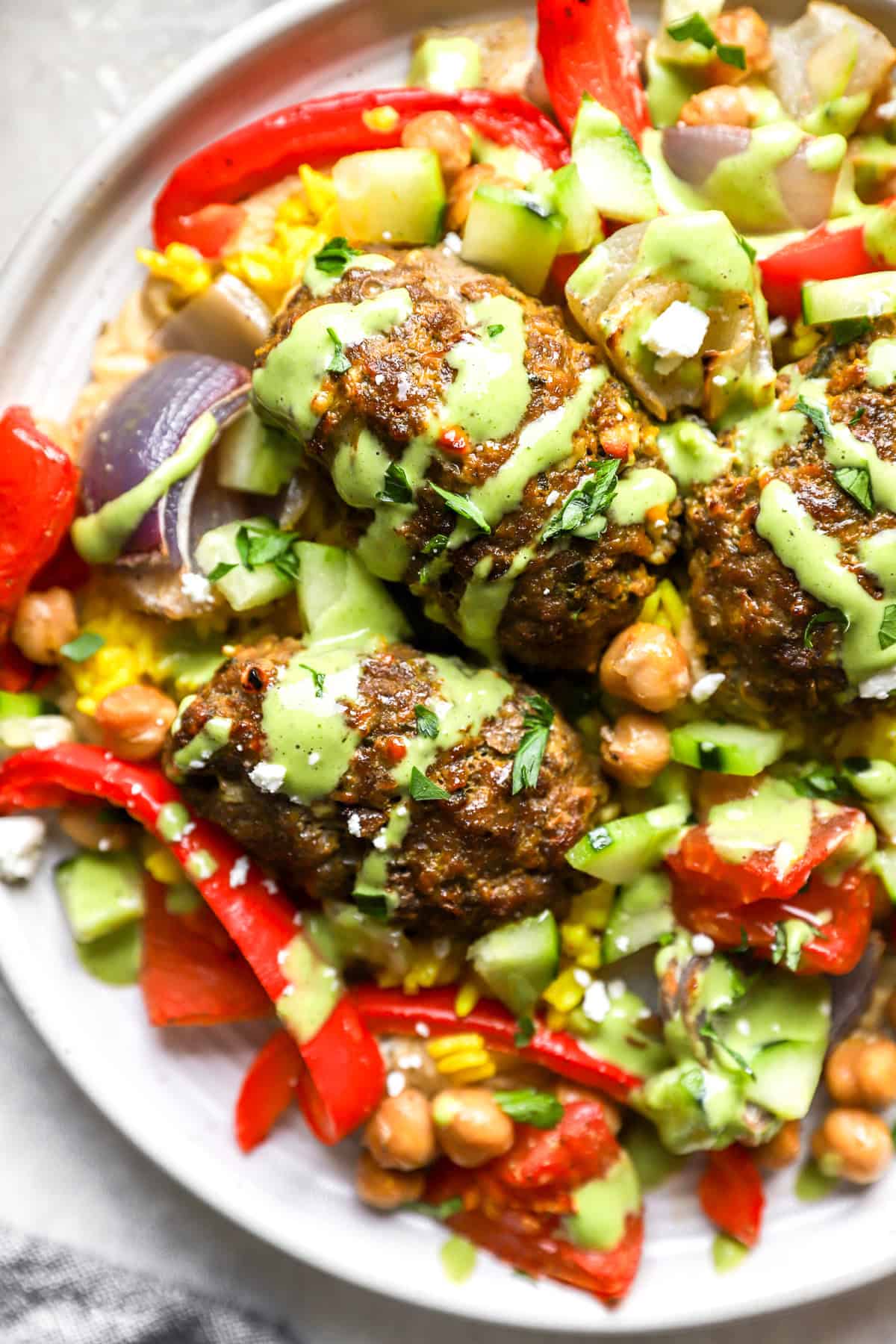 A plate of kofta meatballs with turmeric rice and green tahini. 