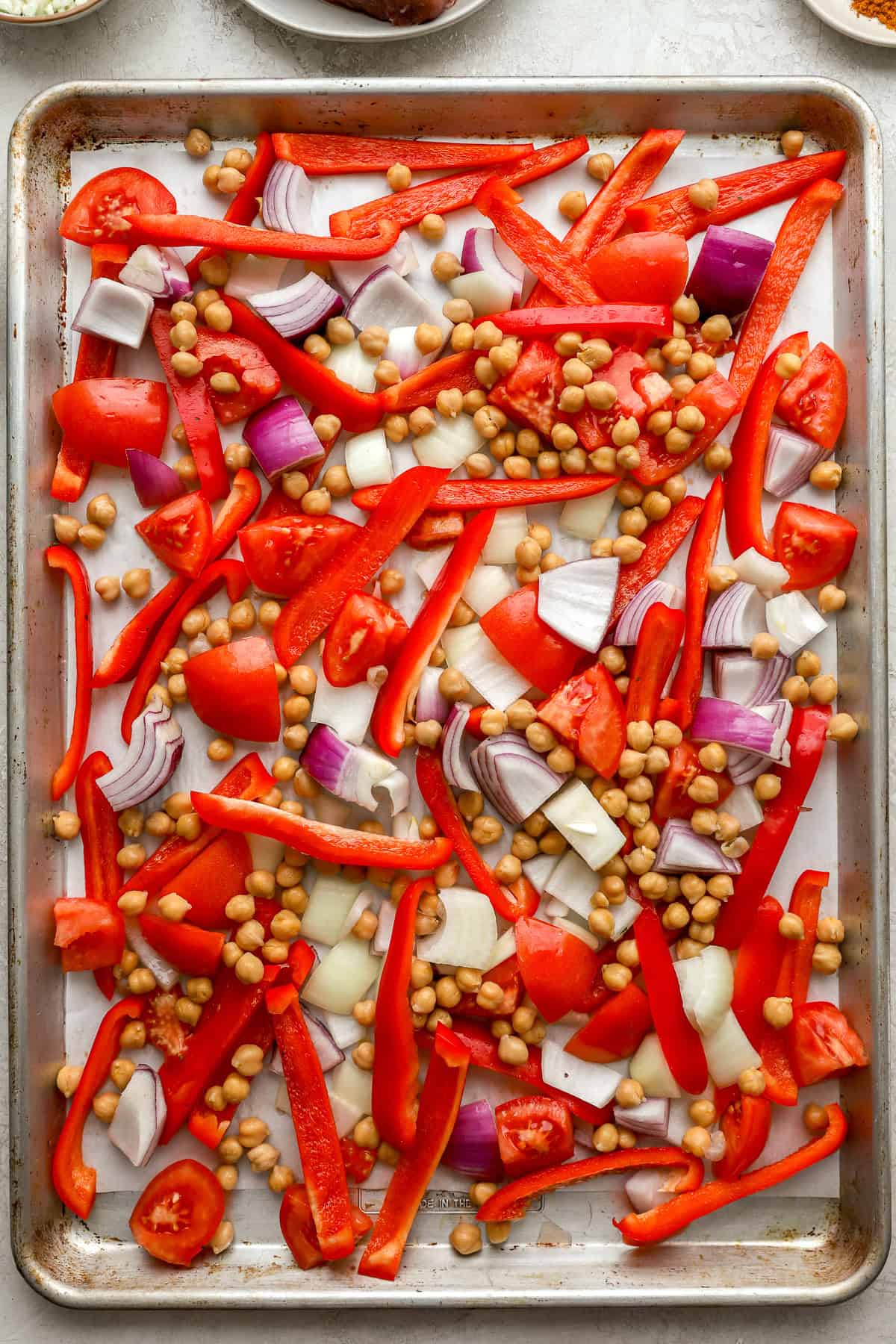 Peppers, onions, and chickpeas on a baking sheet. 