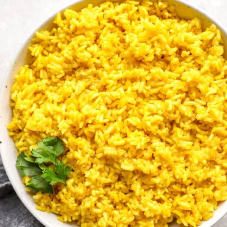 A bowl of turmeric rice with cilantro on top.