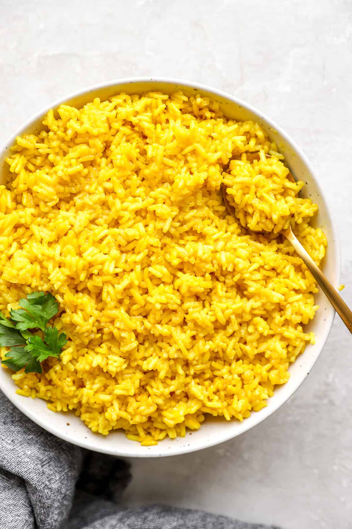 A spoonful of rice on top of a bowl of turmeric rice. 