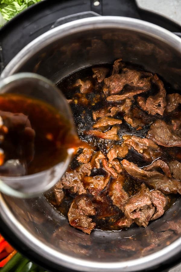 Mongolian sauce being poured over beef in an Instant Pot. 