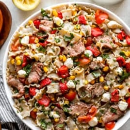 A bowl of chimichurri steak pasta salad with roasted corn and veggies.