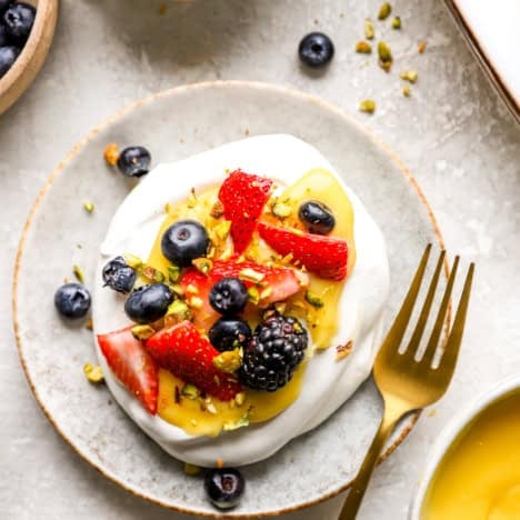 A mini pavlova topped with lemon curd and fresh berries.