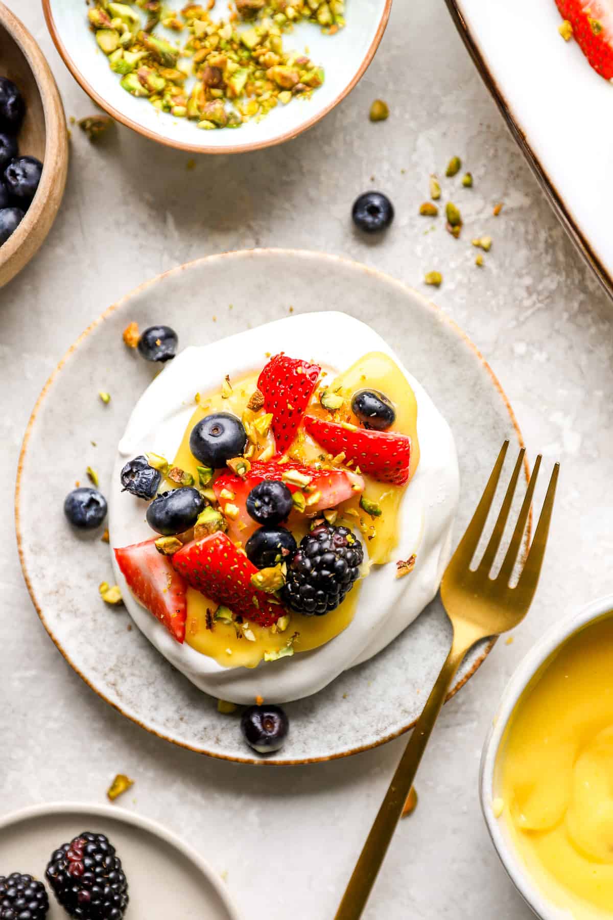 A mini pavlova topped with lemon curd and fresh berries.