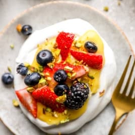 A mini pavlova dessert topped with lemon curd and fresh berries.