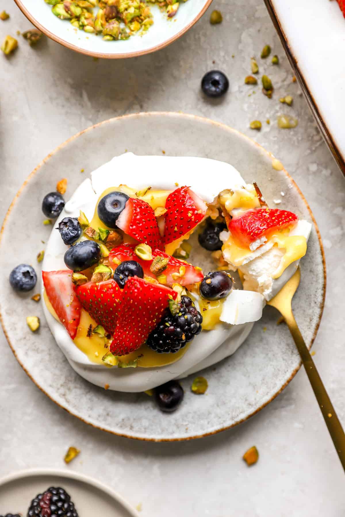 A fork holding a bite of a mini pavlova.