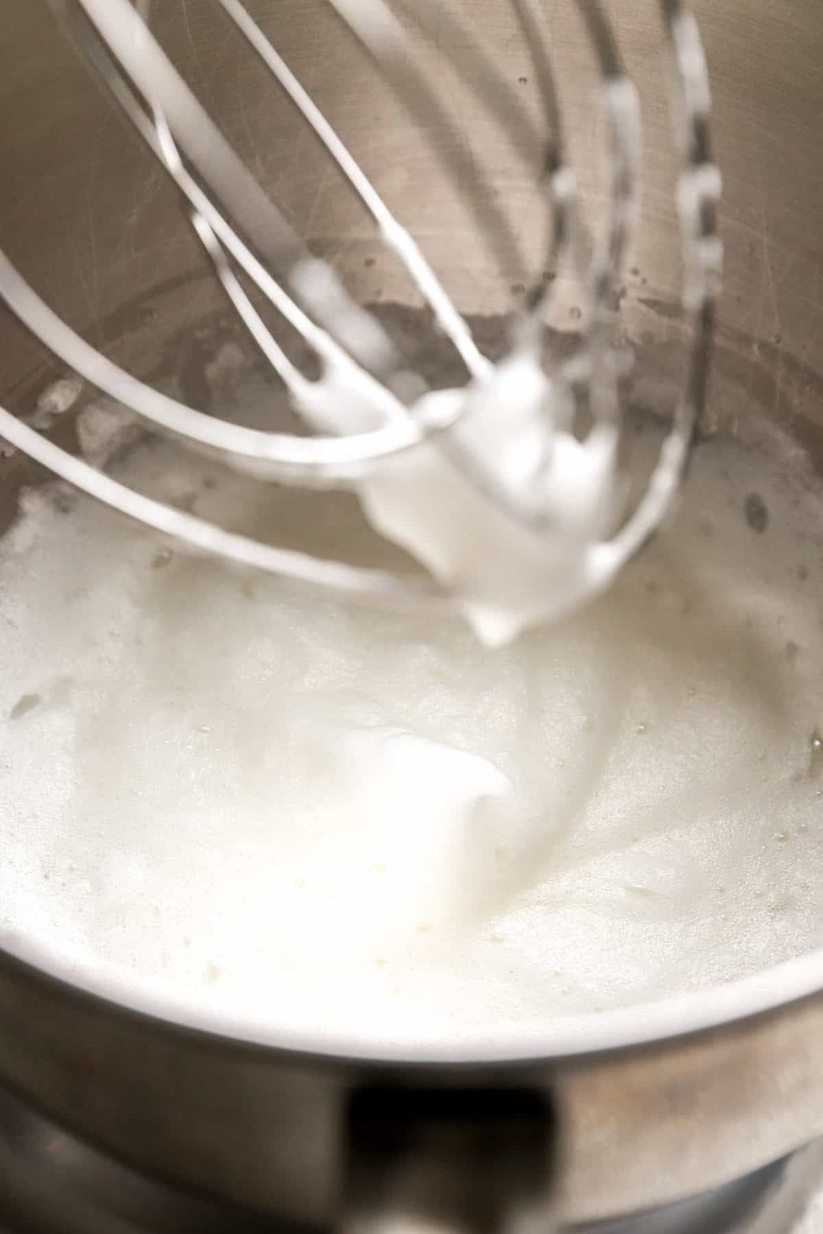 Egg whites being whipped in a stand mixer.