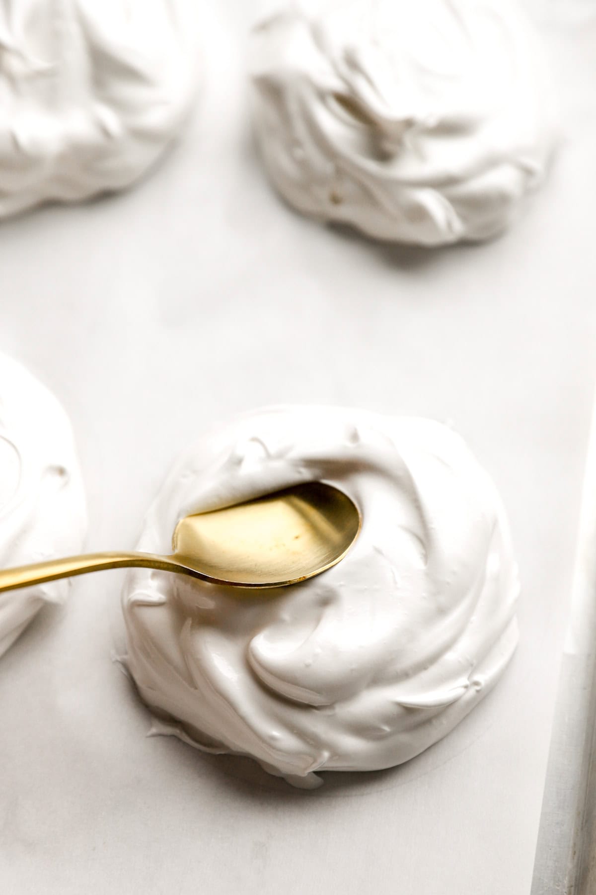 Mini pavlovas being shaped on a baking sheet.