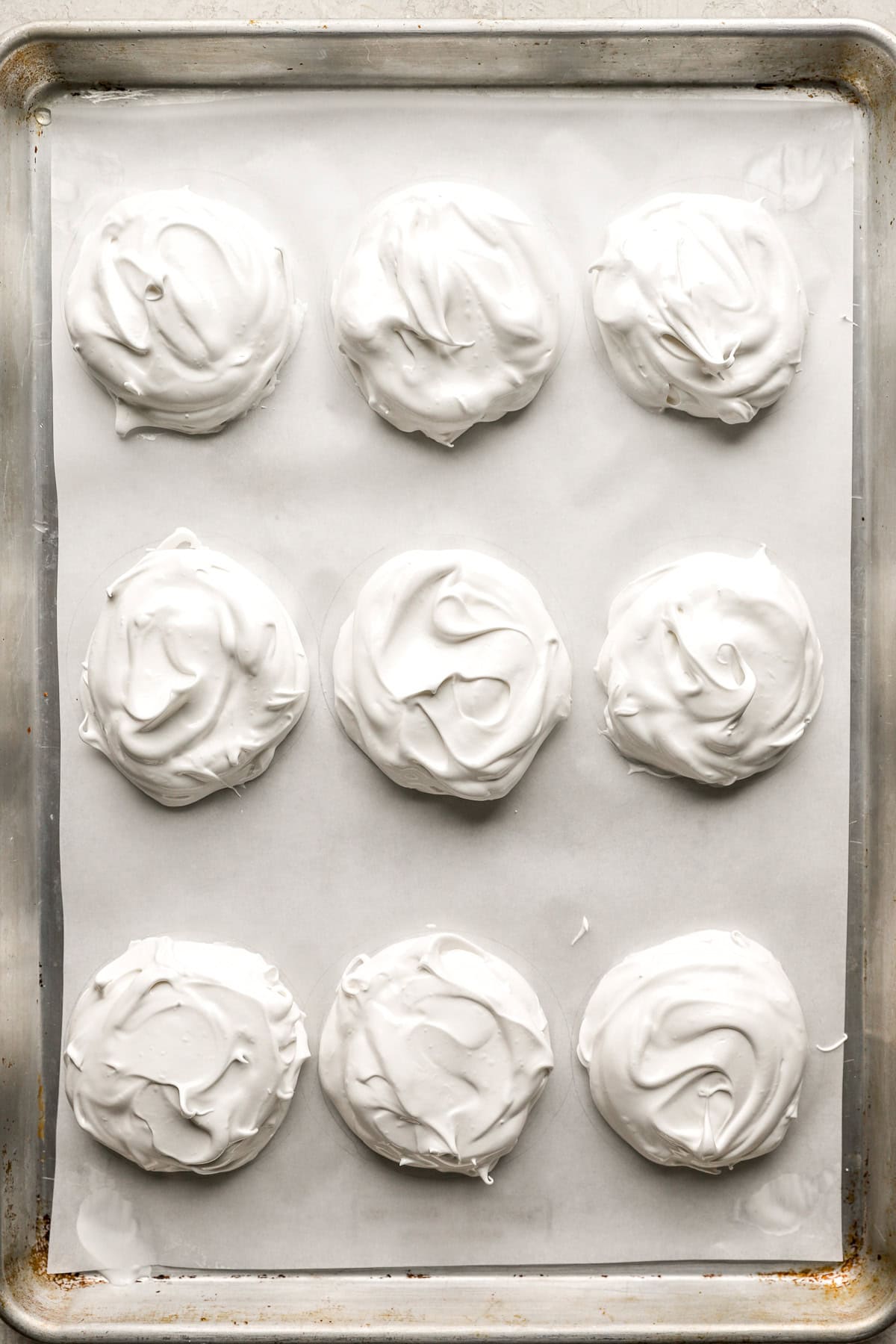 Nine mini pavlovas on a baking sheet.
