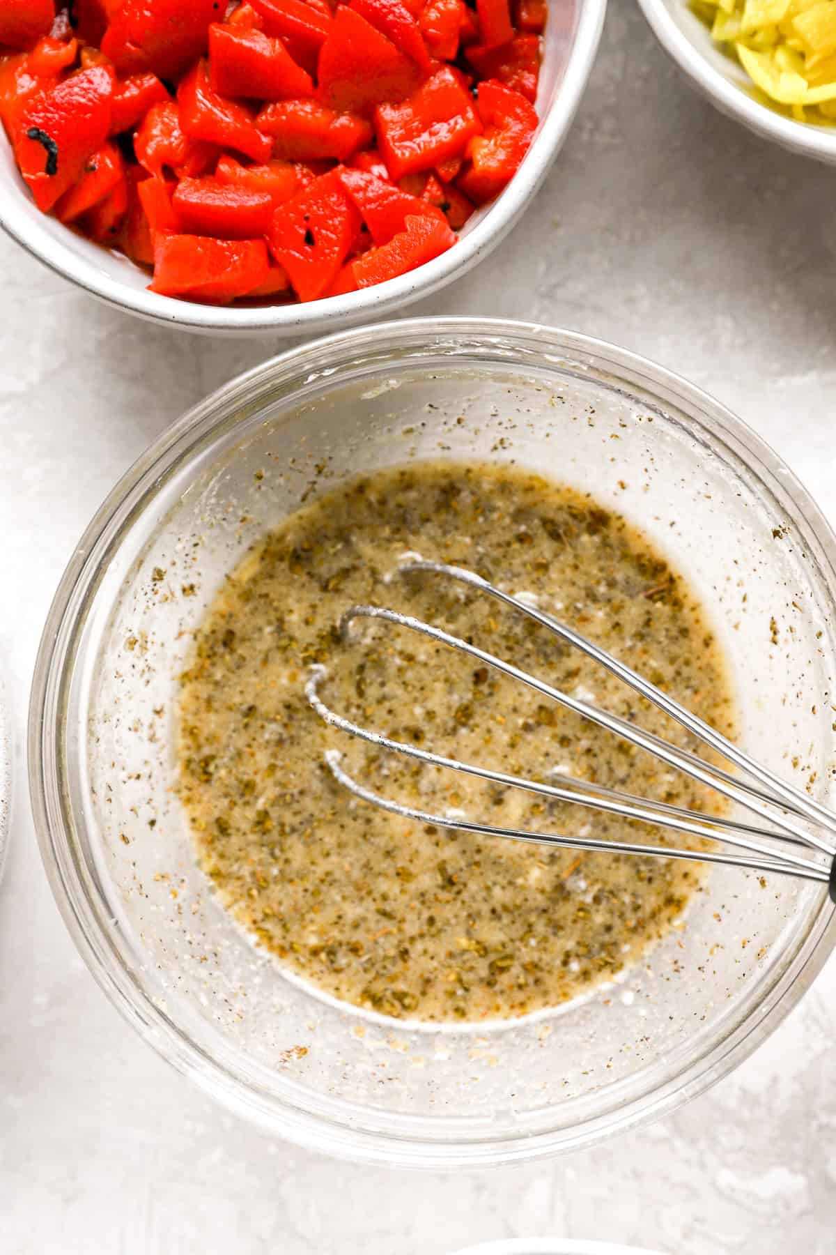 Grinder pasta salad dressing being whisked in a bowl. 