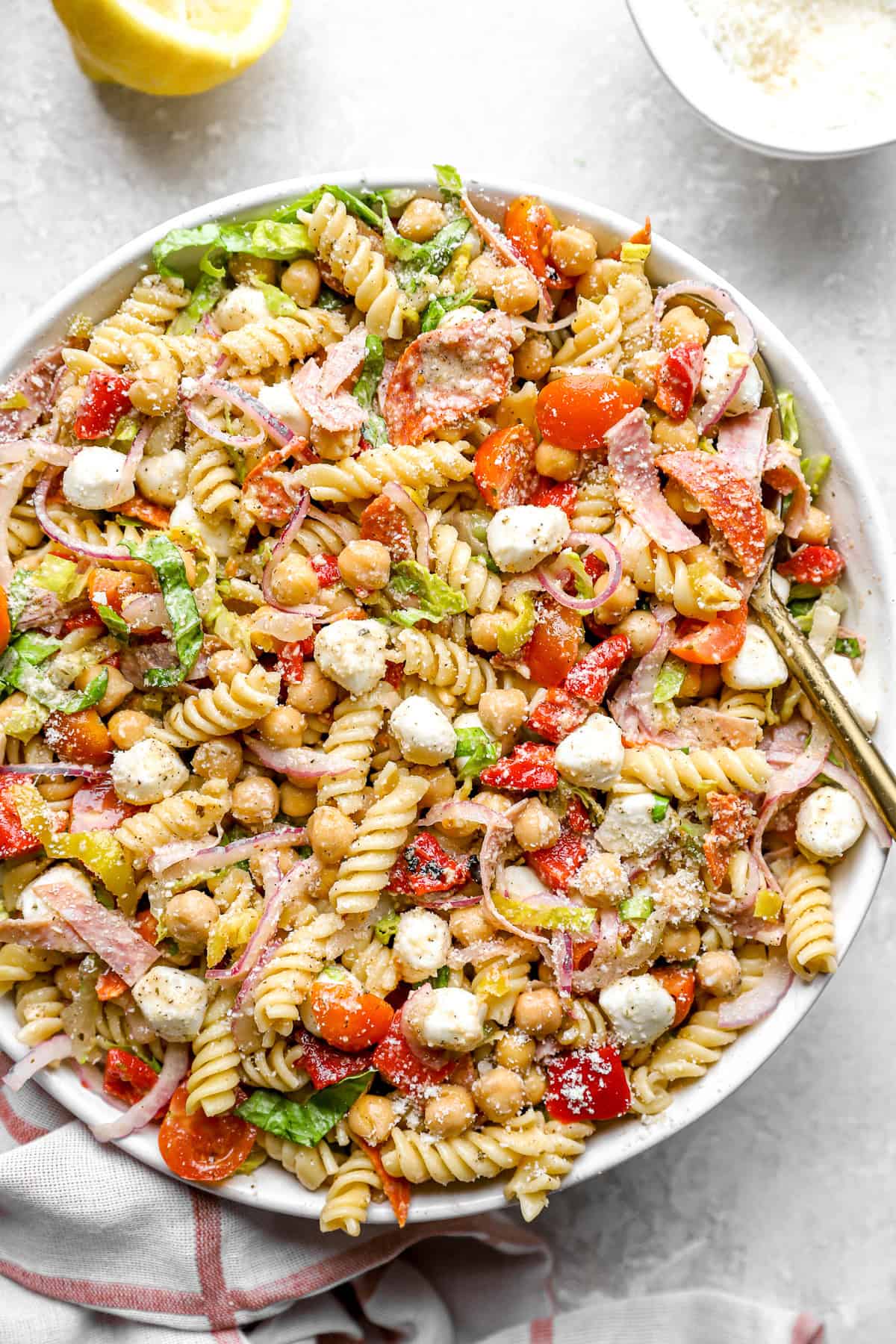 A bowl of Italian grinder pasta salad with a spoon sticking out. 
