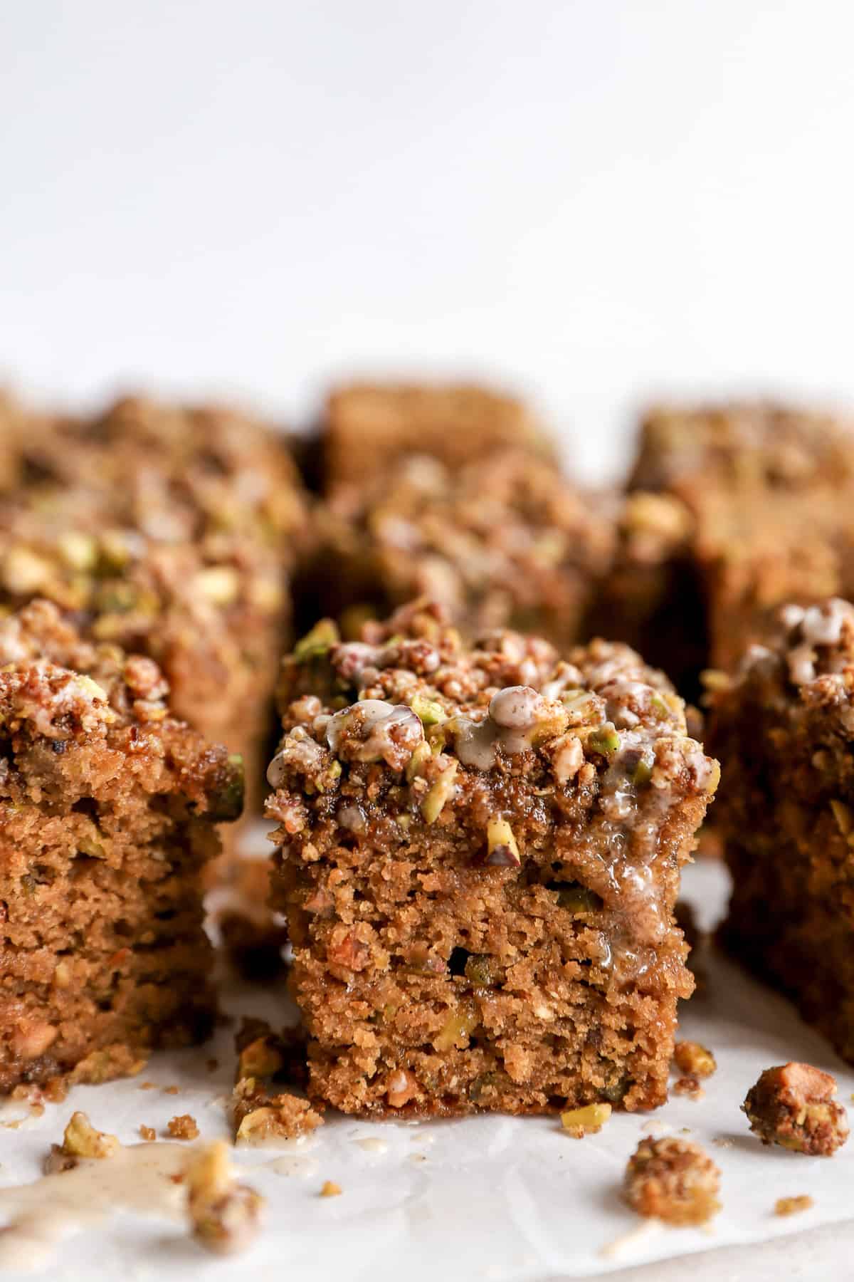 Pistachio cake squares with streusel topping and vanilla glaze. 