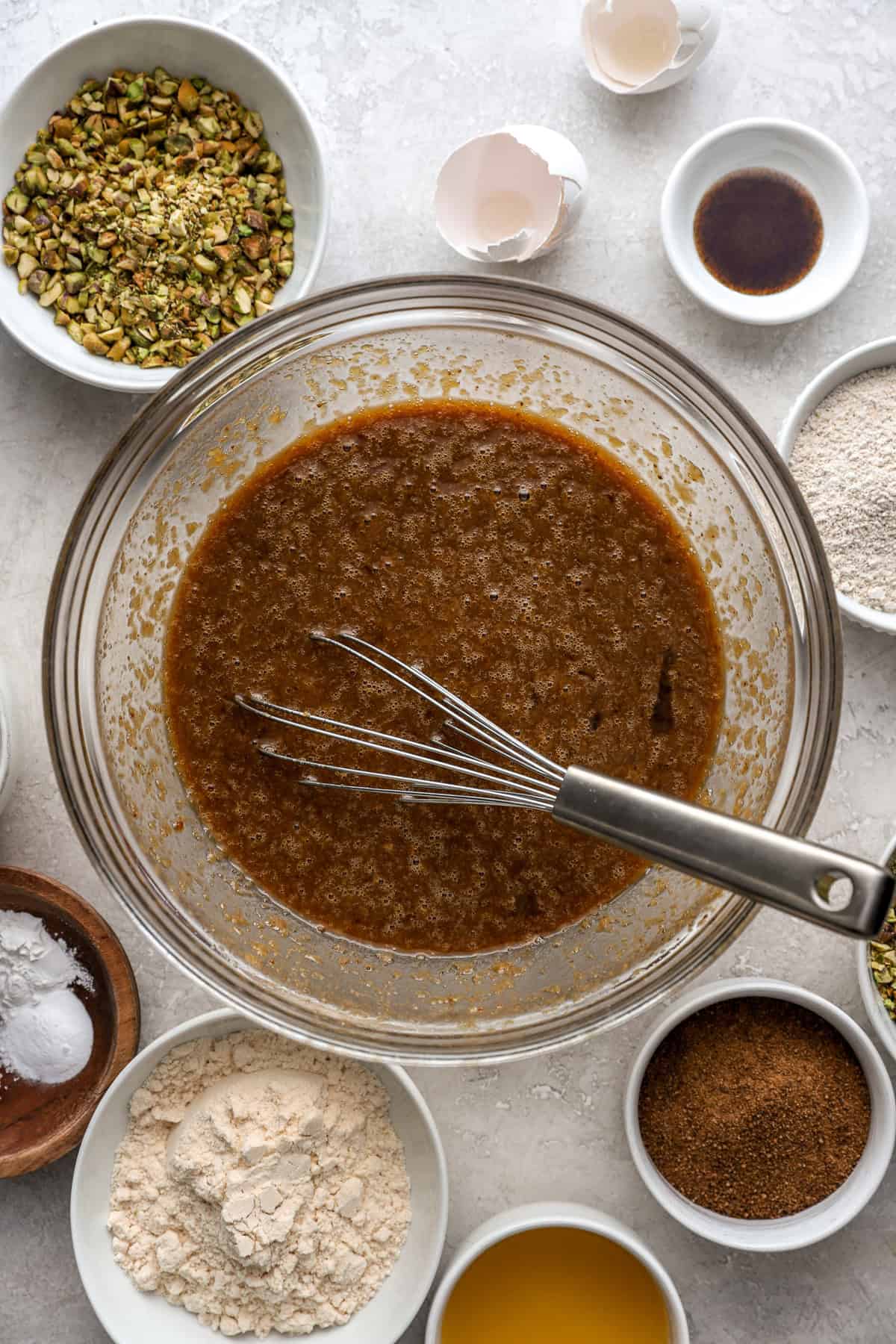 Wet pistachio cake ingredients being whisked in a bowl. 