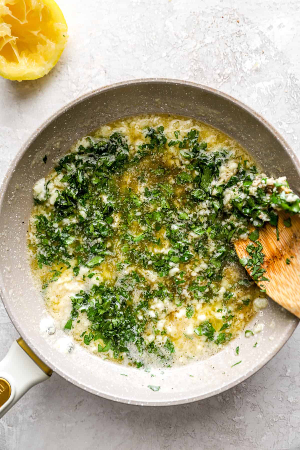 Garlic herb butter being combined in a skillet. 