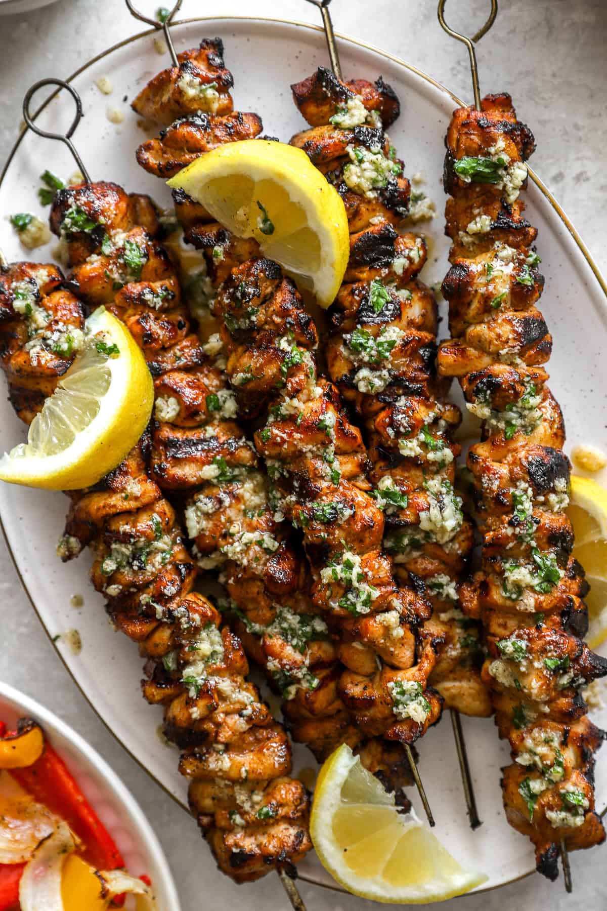 A platter of lemon pepper Parmesan chicken skewers with lemon wedges.