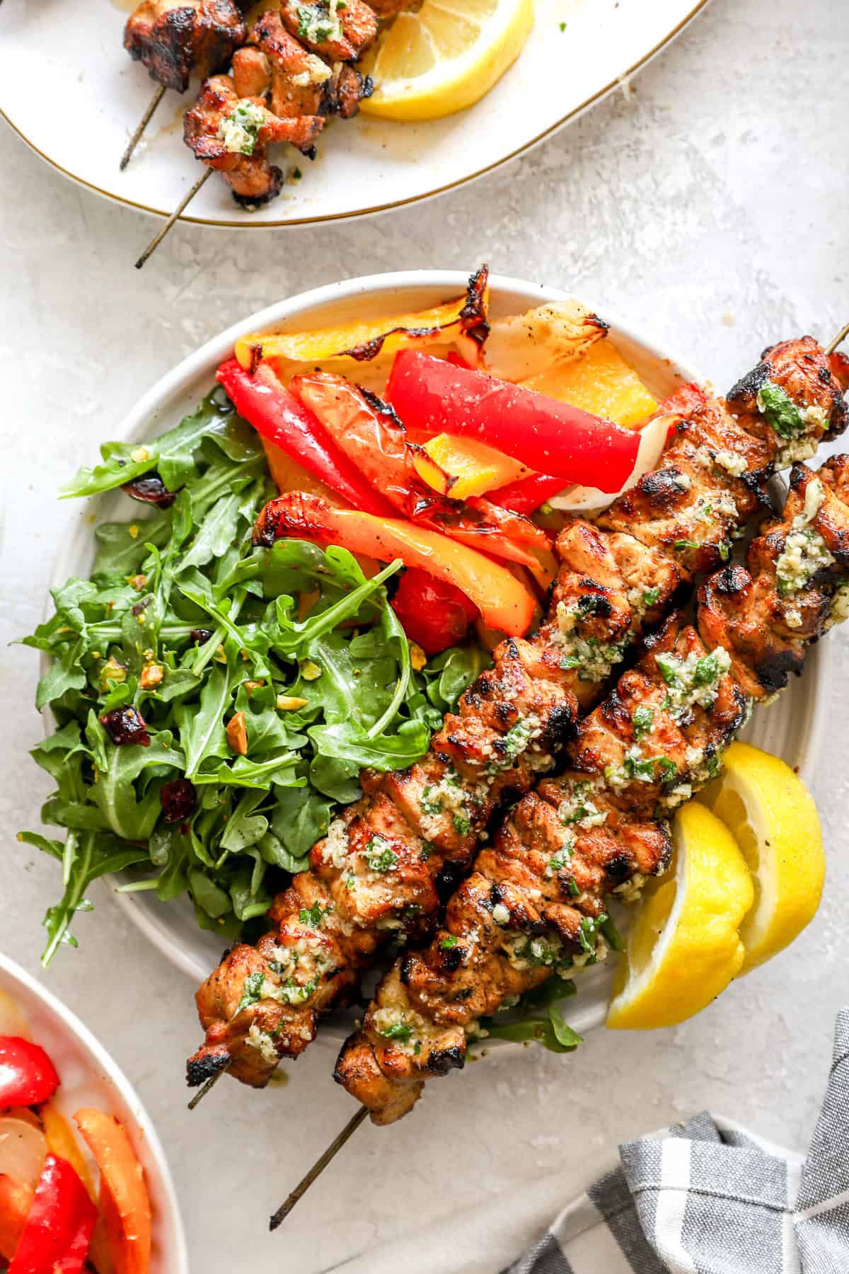 Lemon pepper Parmesan chicken skewers on a plate with veggies.