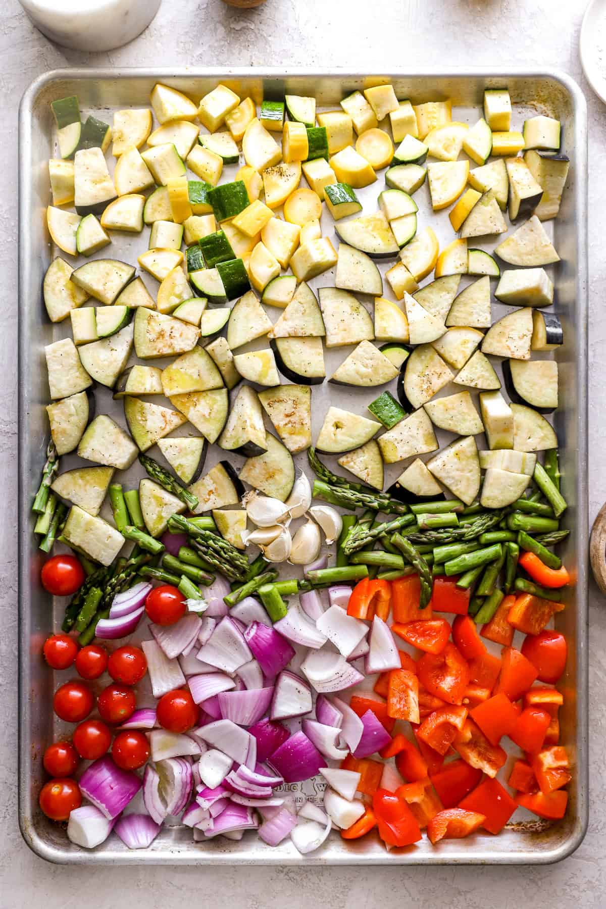 Raw vegetables in an even layer on a baking sheet.