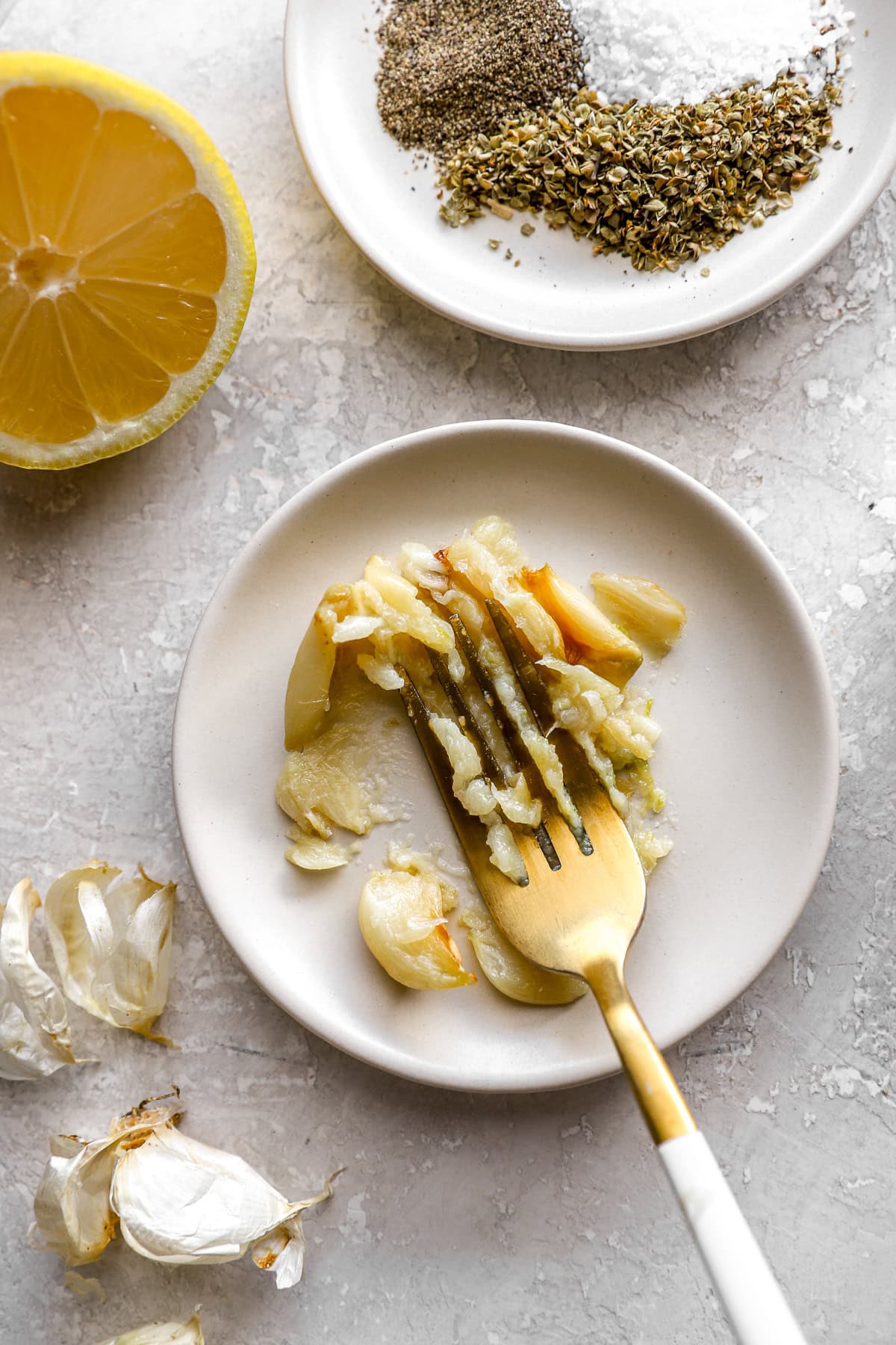 Roasted garlic being smashed on a plate with a fork.