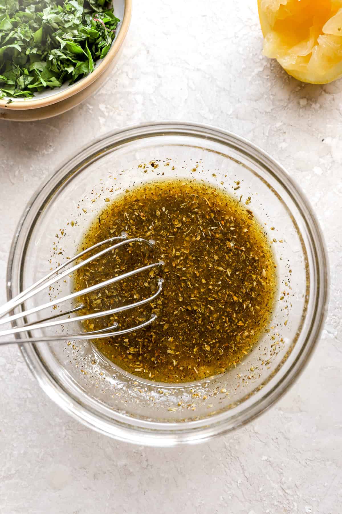 Salad dressing being whisked in a glass bowl.