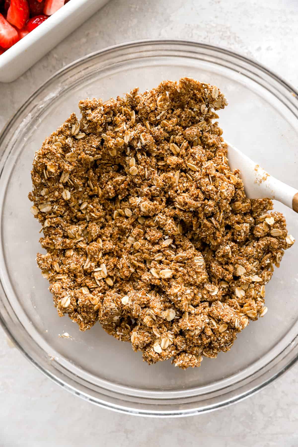 Strawberry crisp topping with oats being stirred in a bowl. 