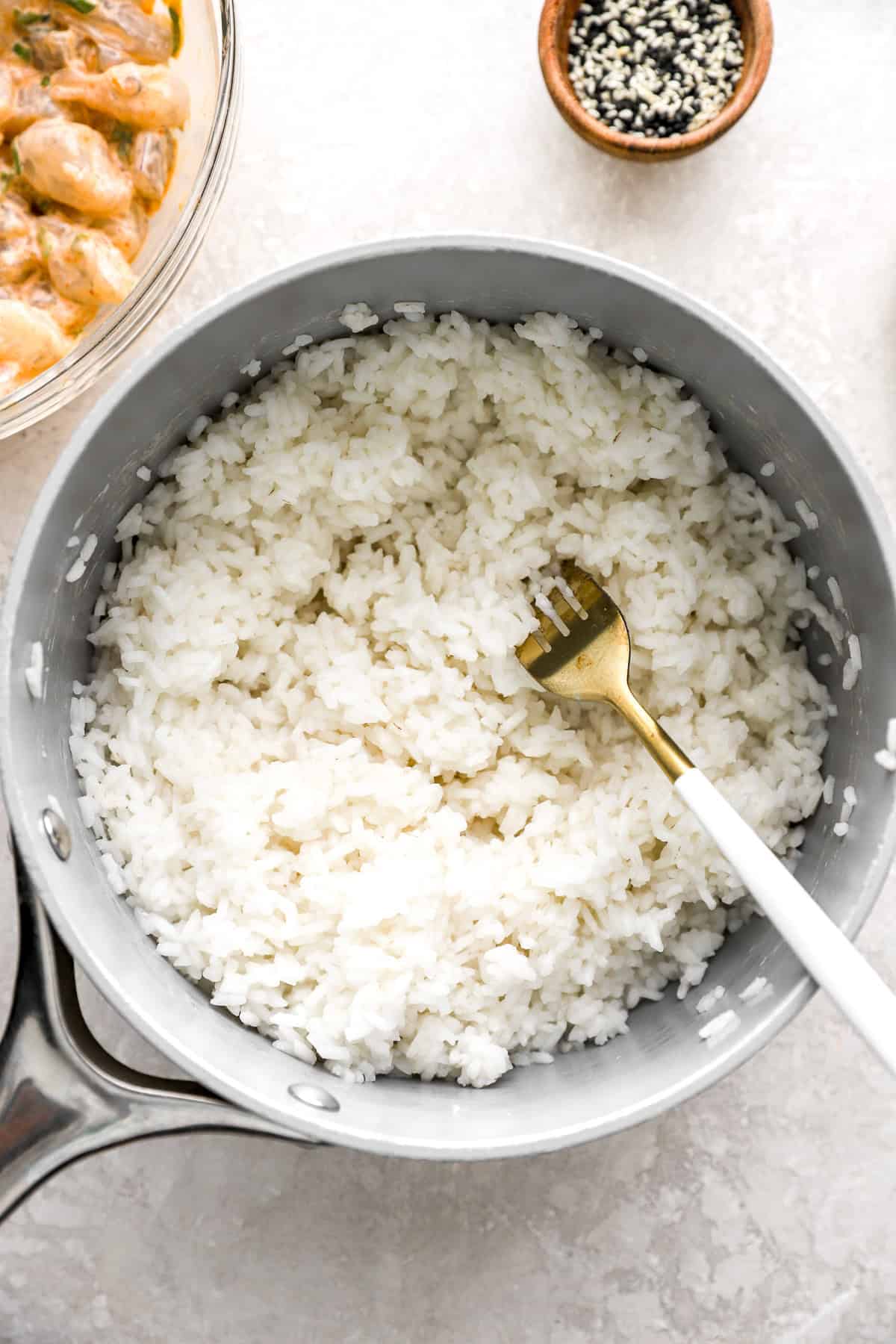 Cooked white rice in a pot with a fork sticking out. 
