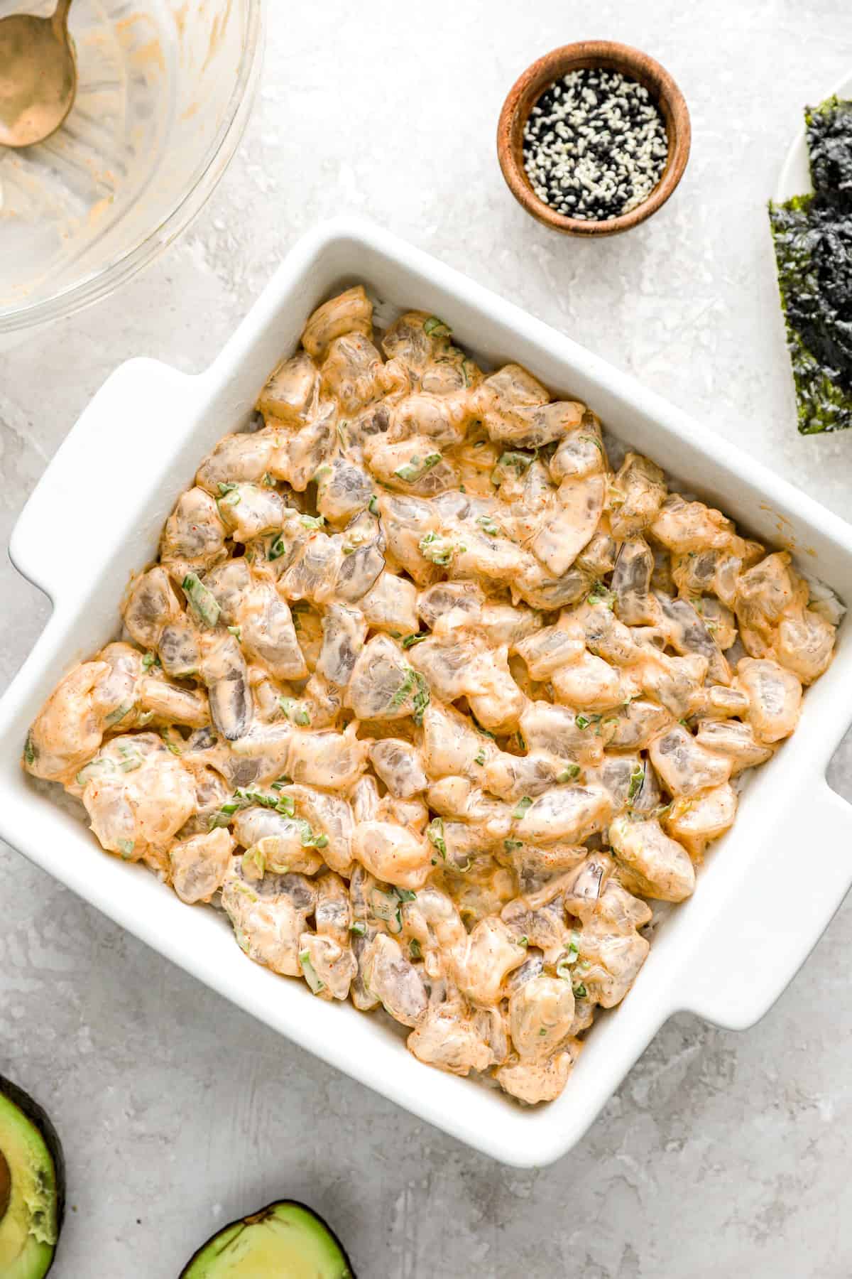 Uncooked shrimp sushi bake in a square dish. 