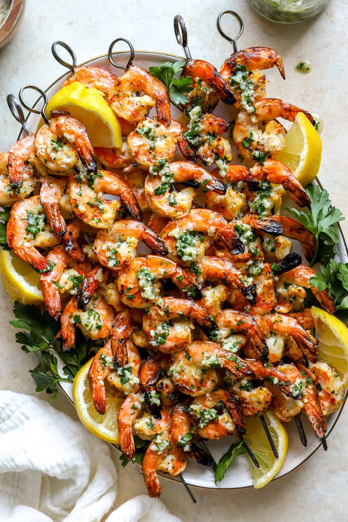 A platter of grilled shrimp skewers with lemon slices. 