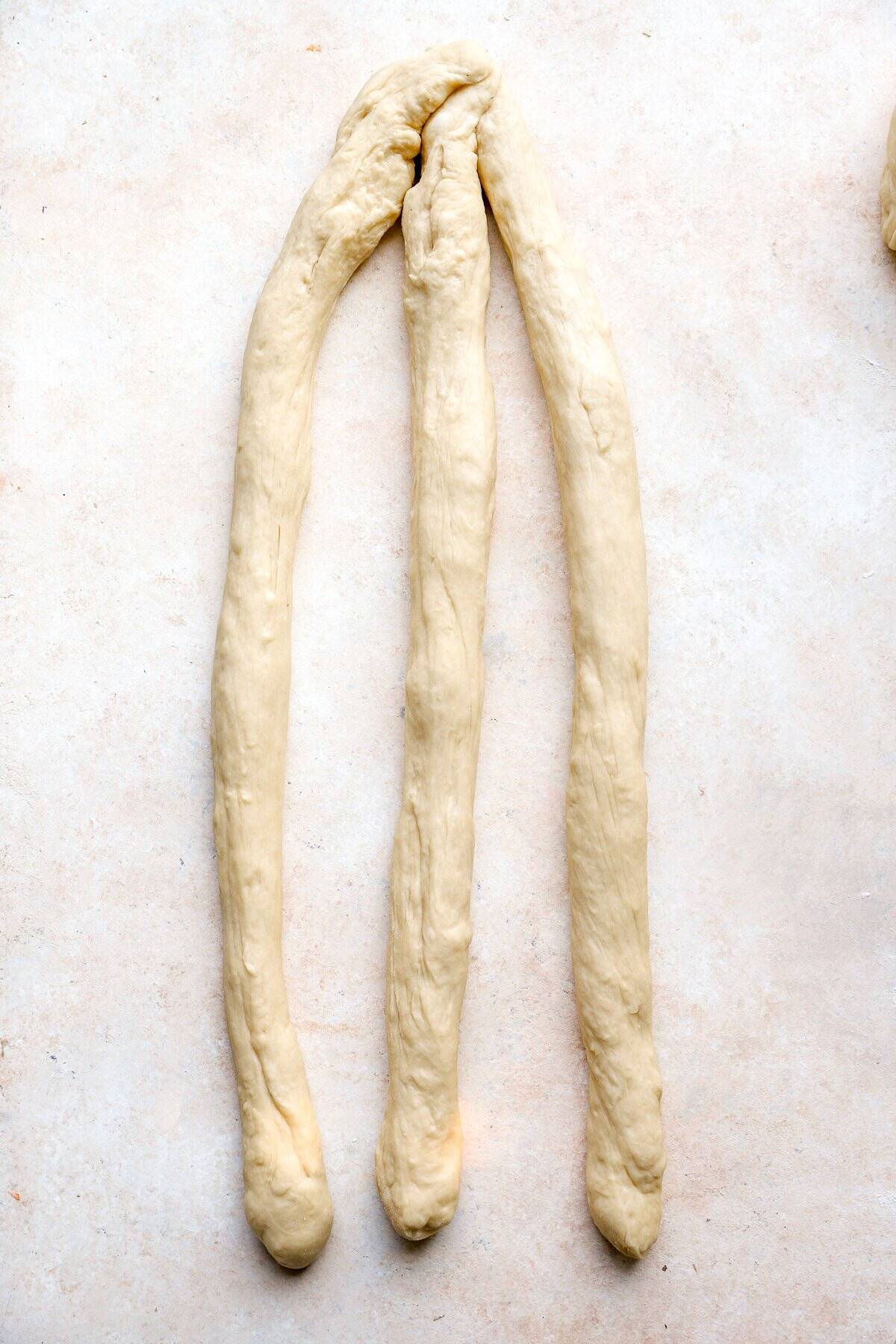 Three strands of Challah dough fused at the top.