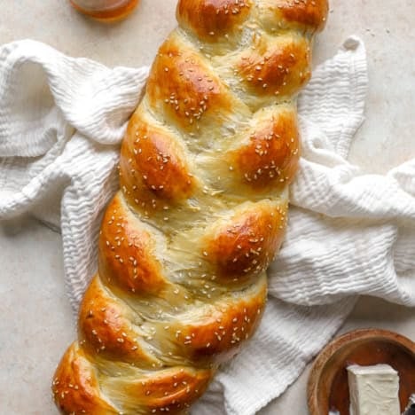 A baked loaf of Challah bread topped with sesame seeds.