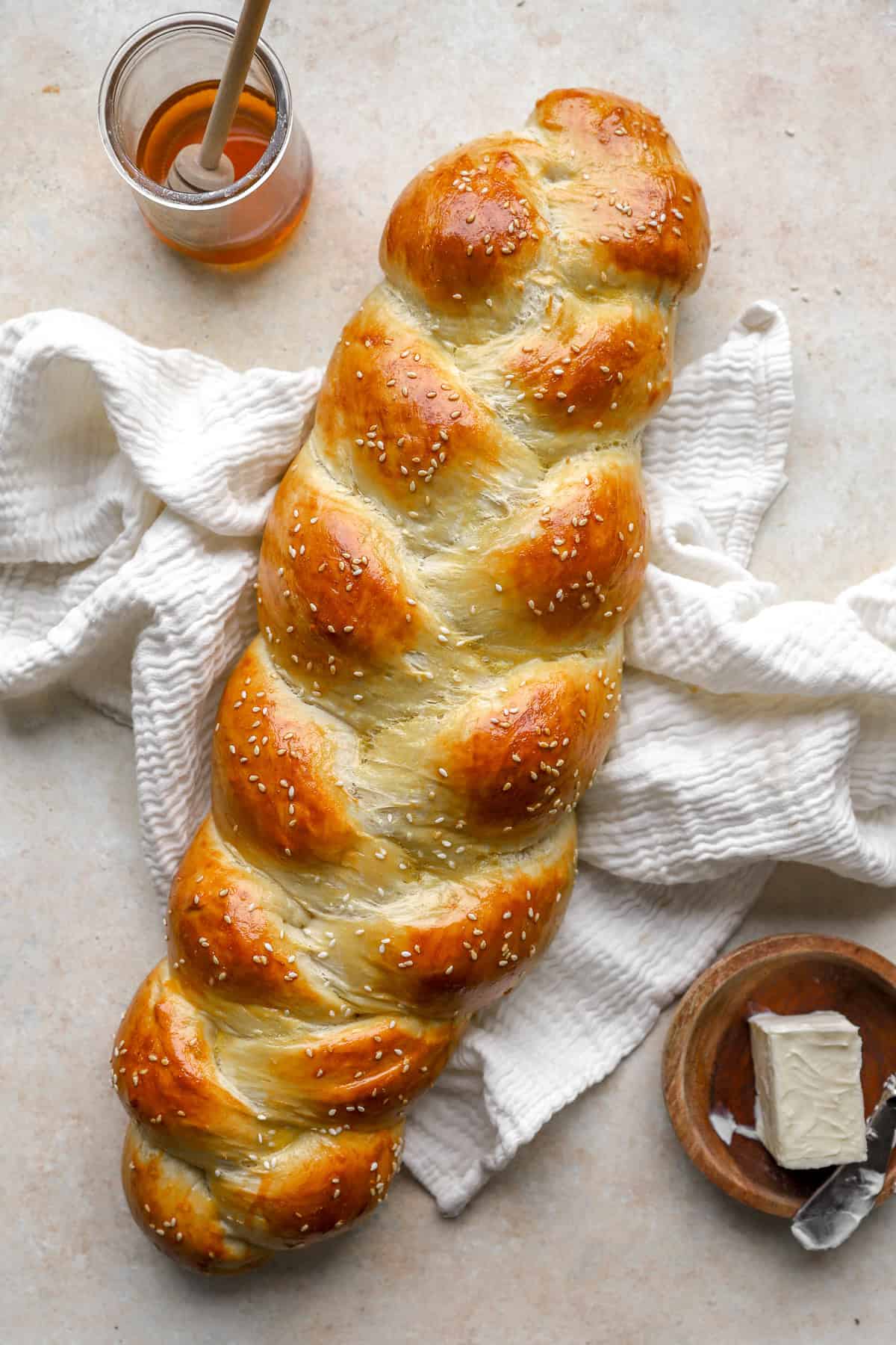 A baked loaf of Challah bread topped with sesame seeds.
