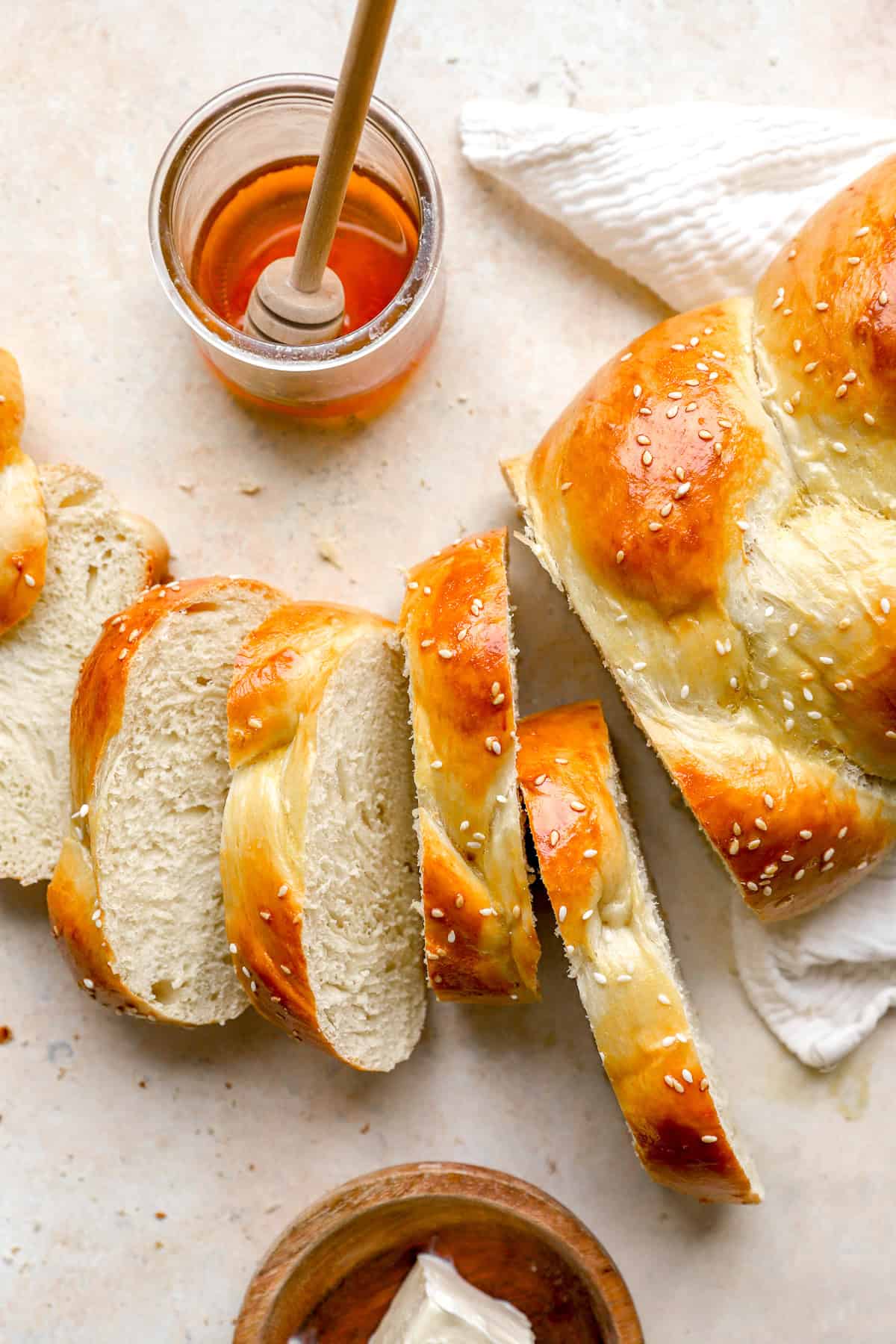 A sliced Challah bread loaf next to a jar of honey.