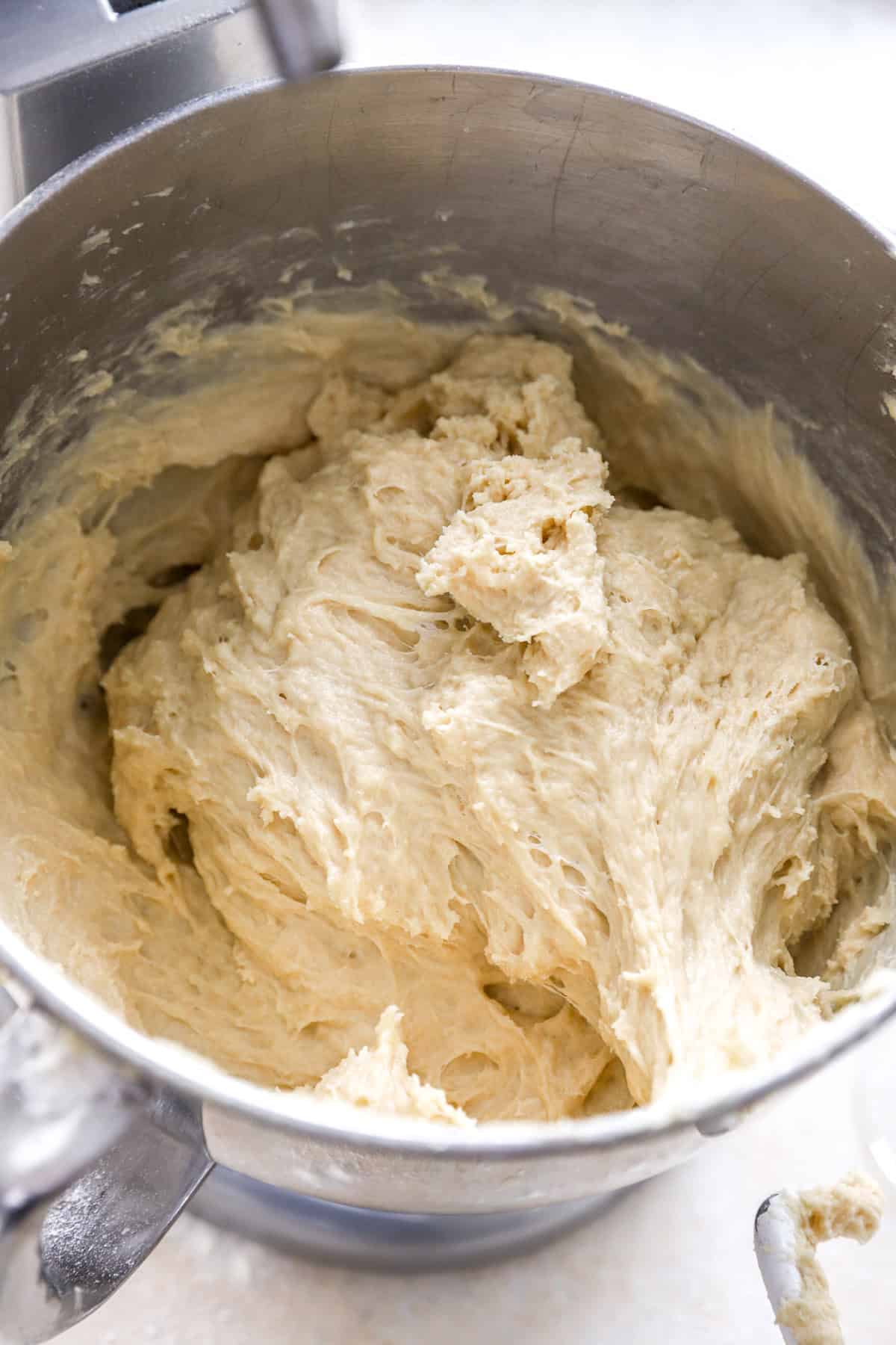 Challah bread dough in a stand mixer fitted with a paddle attachment.