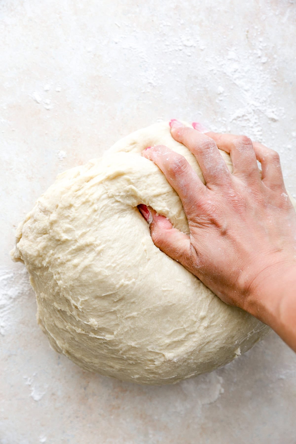 A hand kneading Challah bread dough.