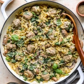 A pot of meatballs with orzo with a wooden spoon on the side.
