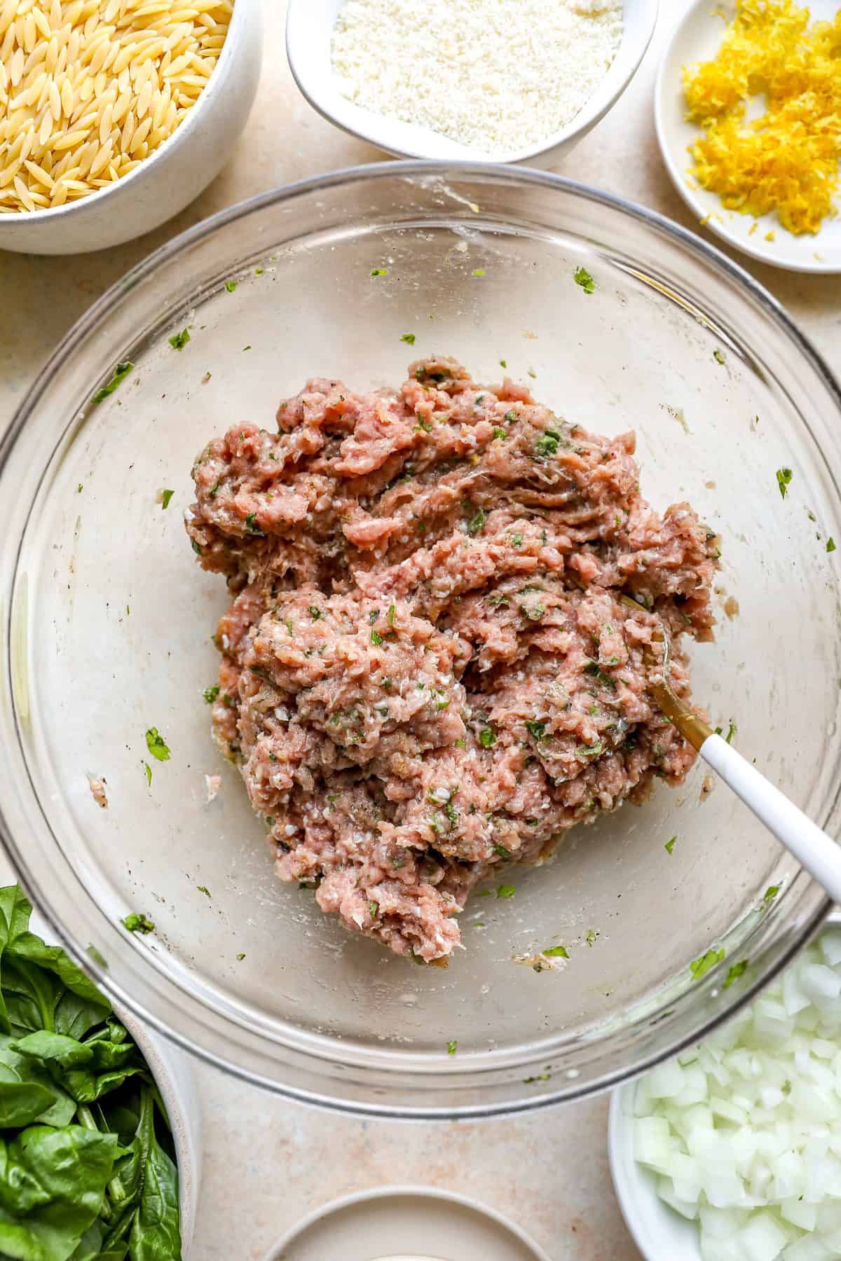Raw meatball mixture in a glass bowl.