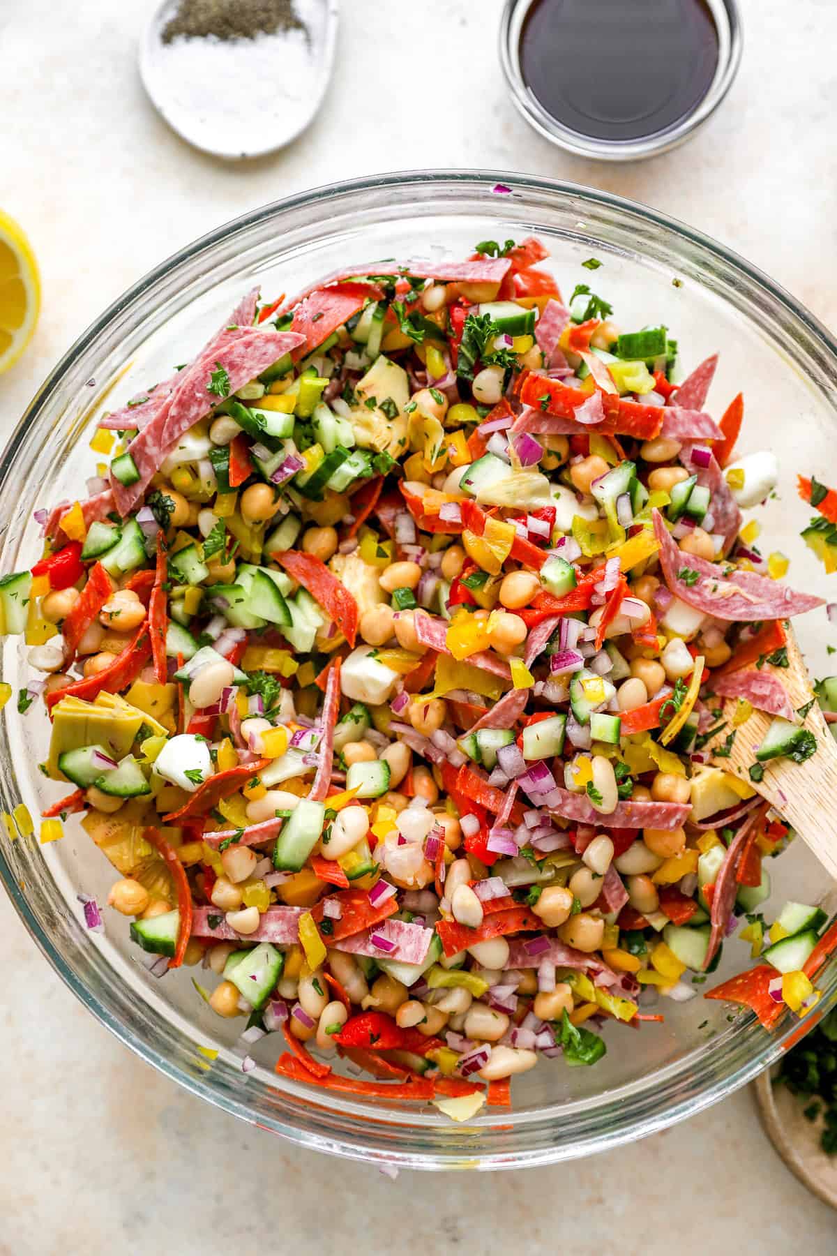 A grinder bean salad being tossed with dressing.