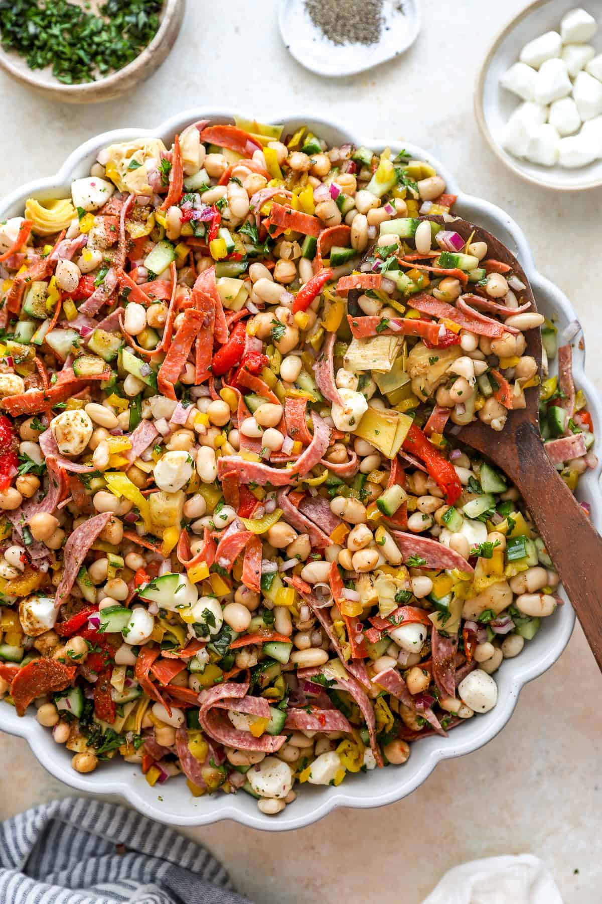 A bowl of grinder bean salad with a wooden spoon sticking out. 