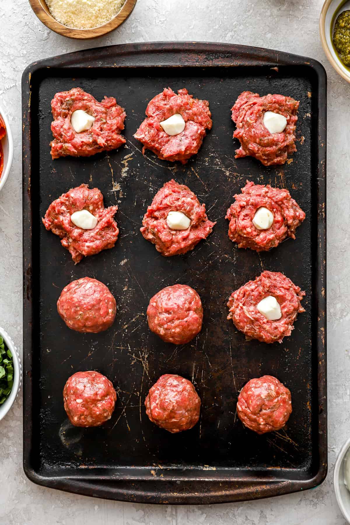 Raw meatballs with a ball of cheese in the center. 