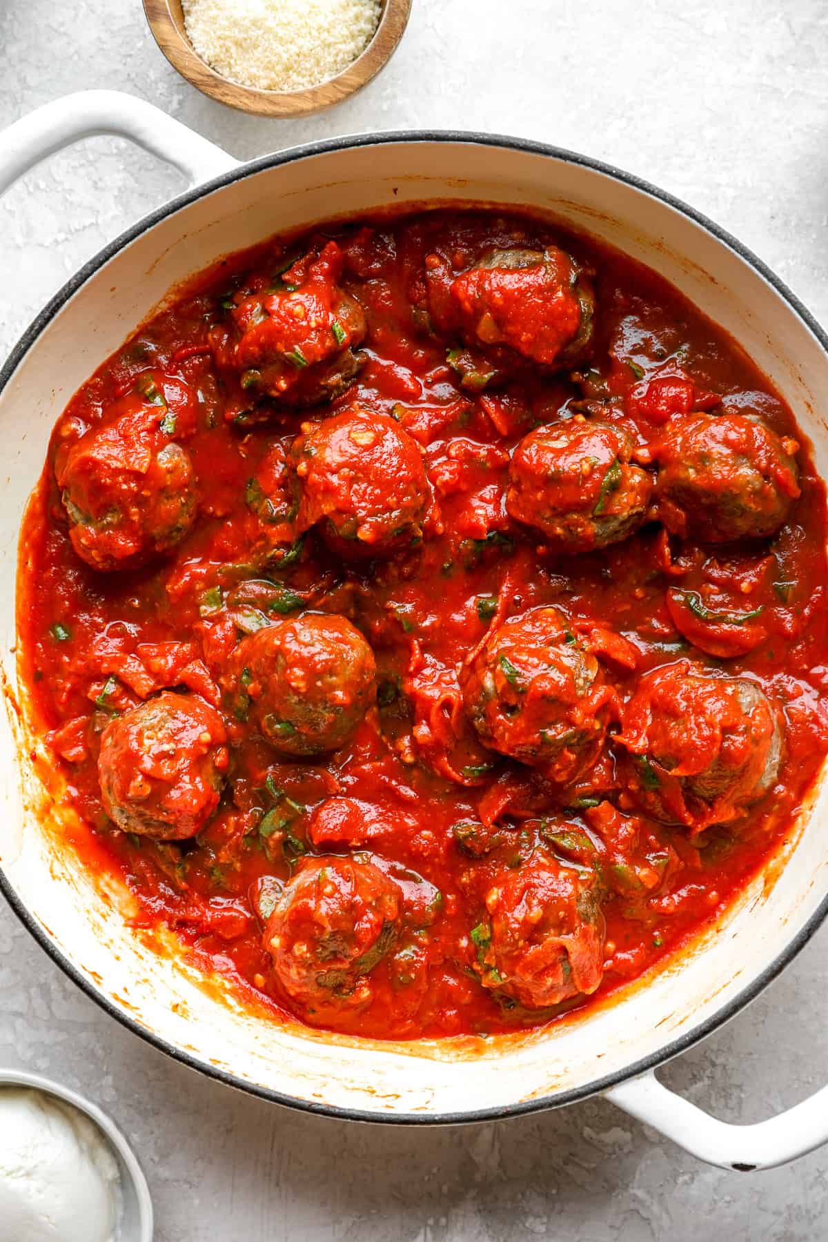 Baked meatballs covered with marinara sauce in a pot. 