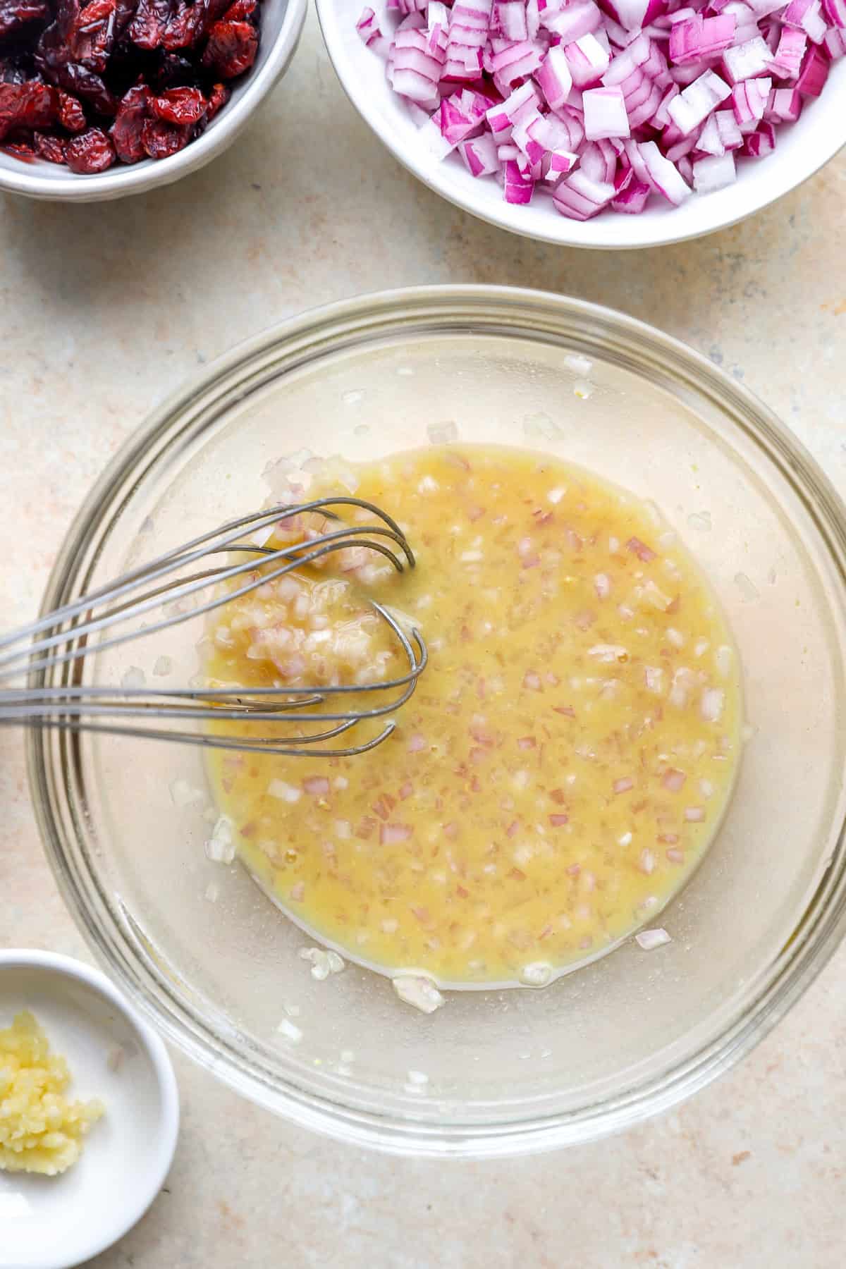 Shallot vinaigrette being whisked in a bowl.