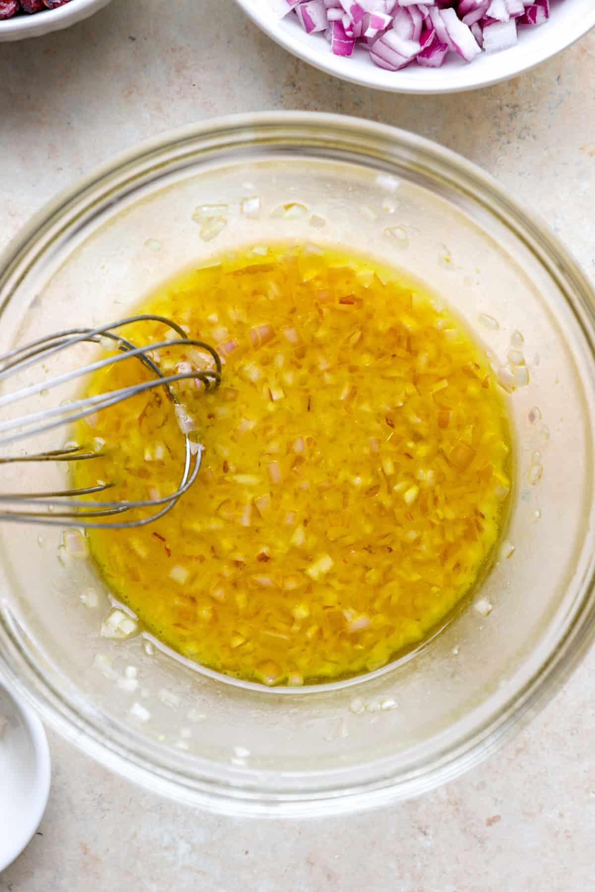 Shallot vinaigrette being whisked in a bowl.