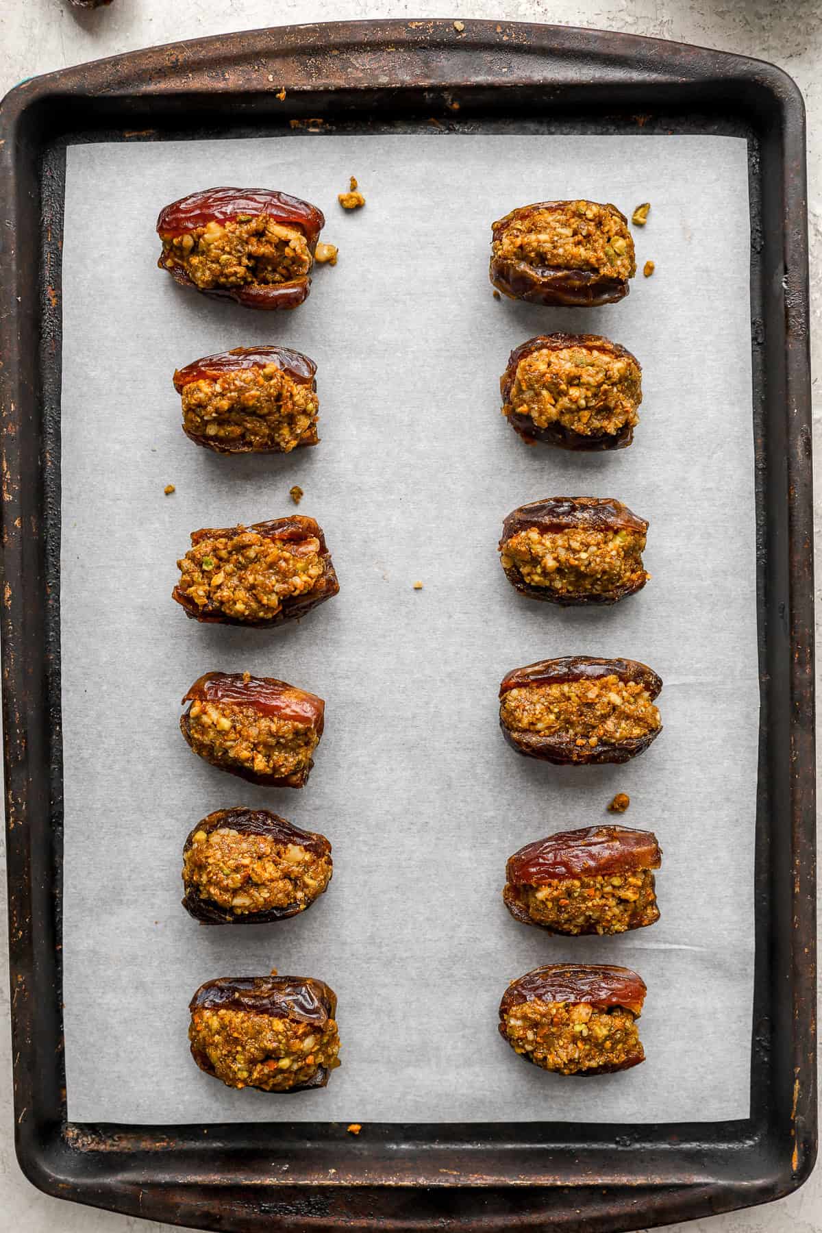 Baklava stuffed dates on a parchment paper lined baking sheet.
